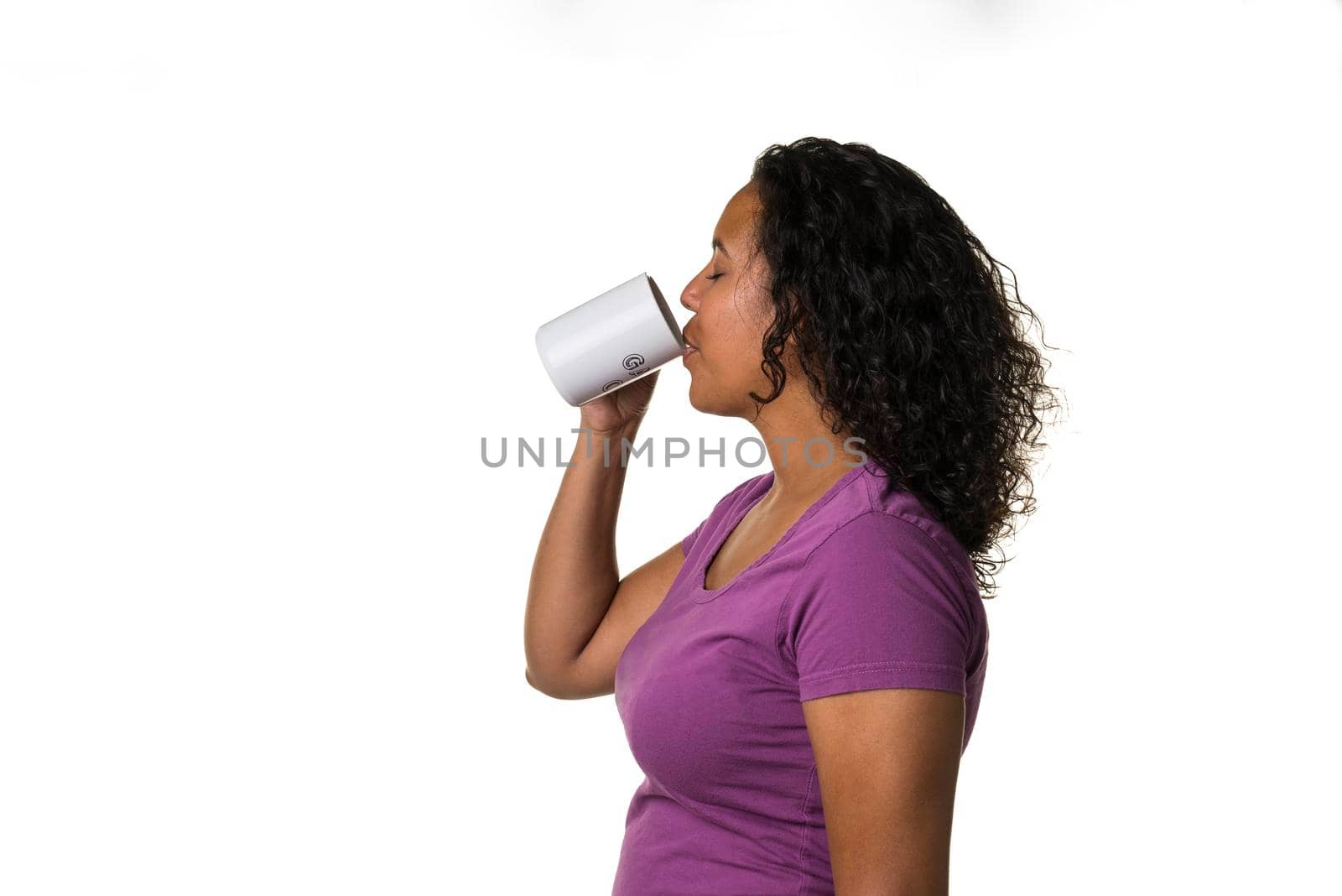 Young mixed race woman in purple shirt drinking a hot liquid from a black and white cup isolated with a white background by LeoniekvanderVliet