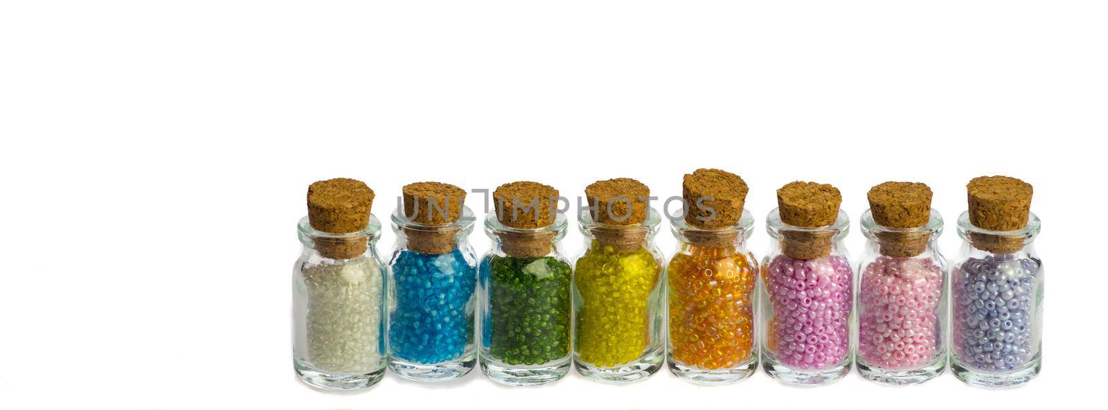 Little bottles in a row with colorful beads isolated on a white background, banner for facebook