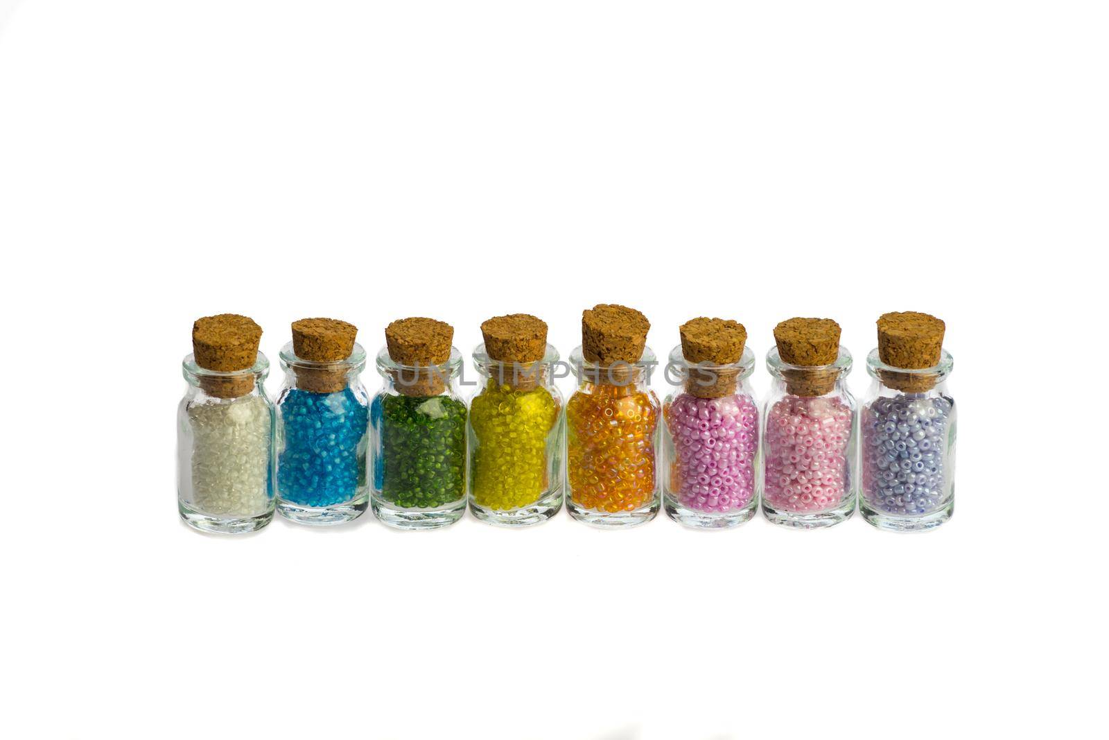 Little bottles in a row with colorful beads isolated on a white background, with copy space by LeoniekvanderVliet