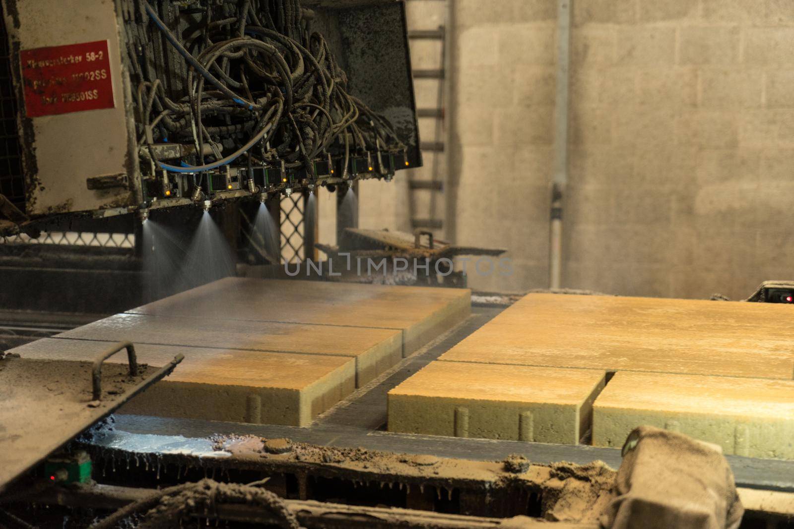 Kampen - The Netherlands - May 11 2017 - Production line where concrete paving tiles are impregnaned with waterresistant substance spraying