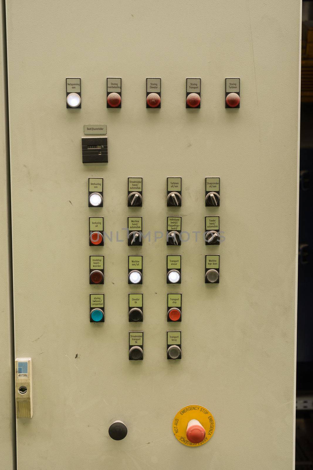 Close up of electric control panel with switches, multi colored indicators and an emergency stop