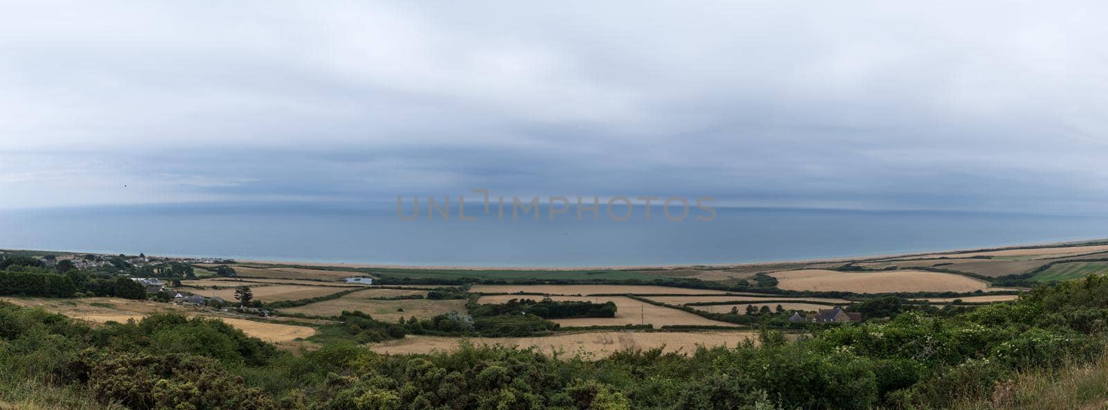 A South Dorset coastline near Weymouth, England. With meadows, clouds and deep blue sea. Panorama and banner