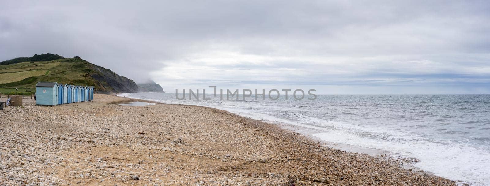 Blue beach holiday house by the English Channel on Jurassic coast in Charmouth, Dorset, United Kingdom, UK. British summer holidays, hilly countryside, beach summer destination.