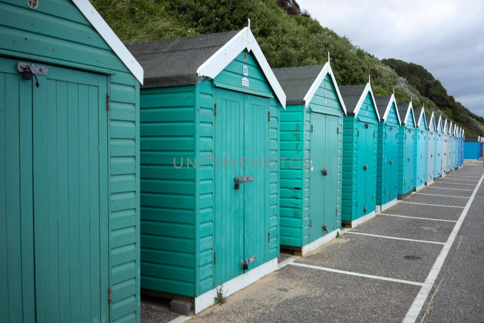 Colorful Beach huts, in green and blue colors, at the  boulevard in Bournemouth, Dorset, UK, England on a cloudy day in summer by LeoniekvanderVliet