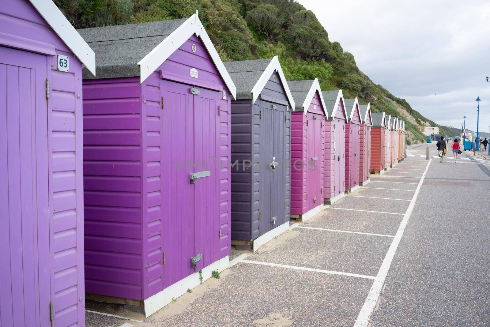 Colorful Beach huts, in purple and pink colors, at the  boulevard in Bournemouth, Dorset, UK, England on a cloudy day in summer by LeoniekvanderVliet