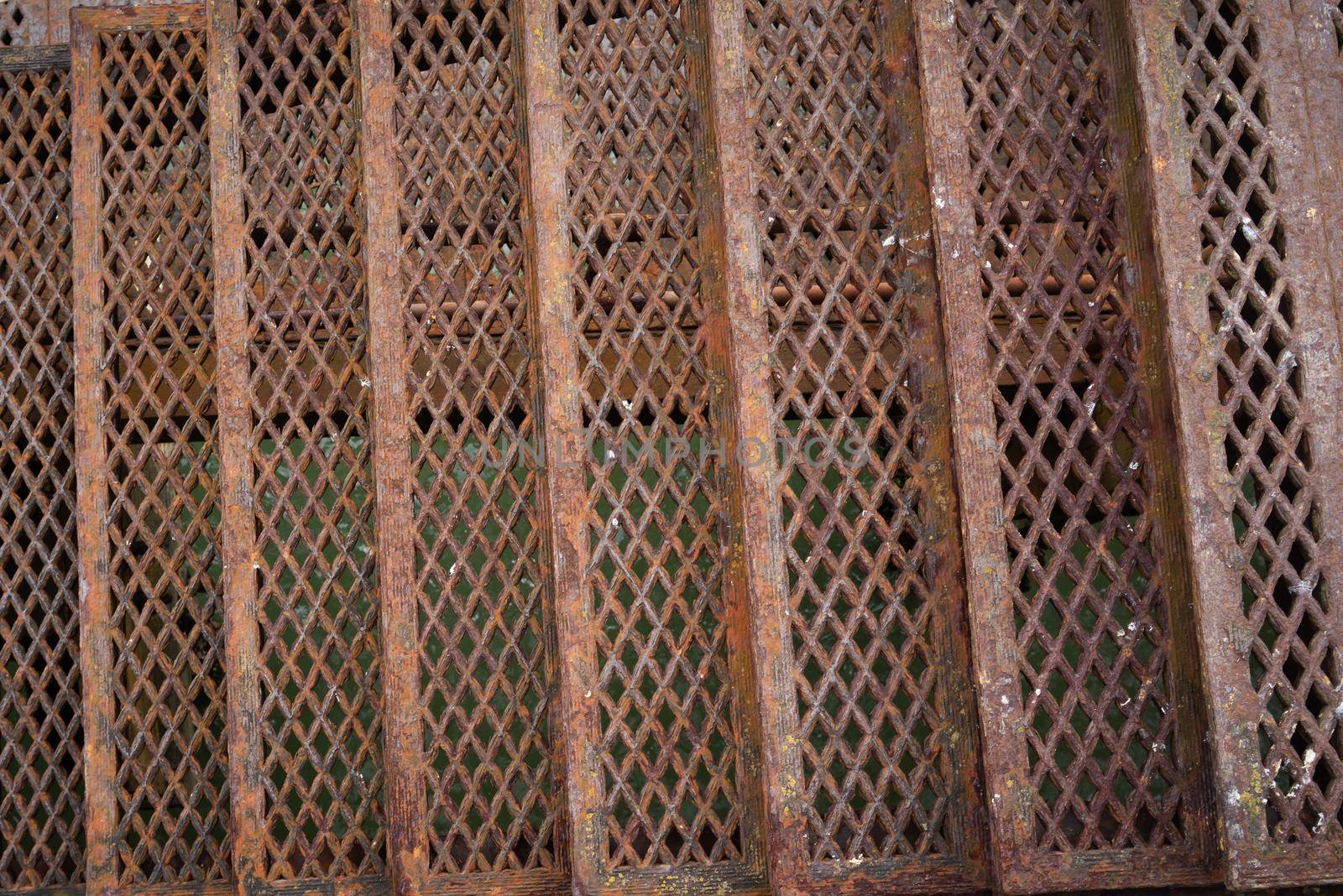 a set of Rusty metal stairs going down with steps, pattern of red weathered iron and structure, antique, above water