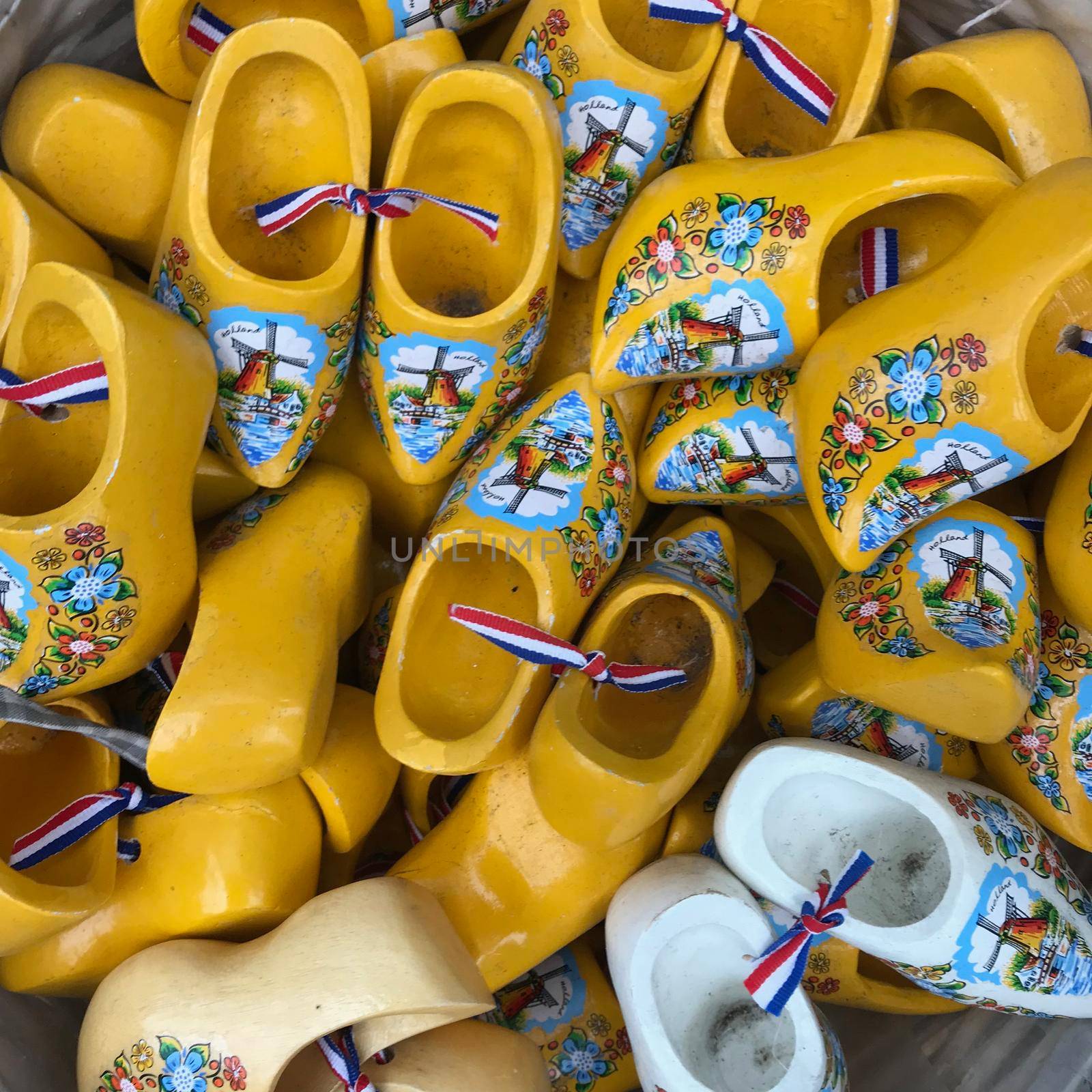 a Large group of Tourist gifts shaped like little clogs with windmills and flowers in a basket in yellow and white