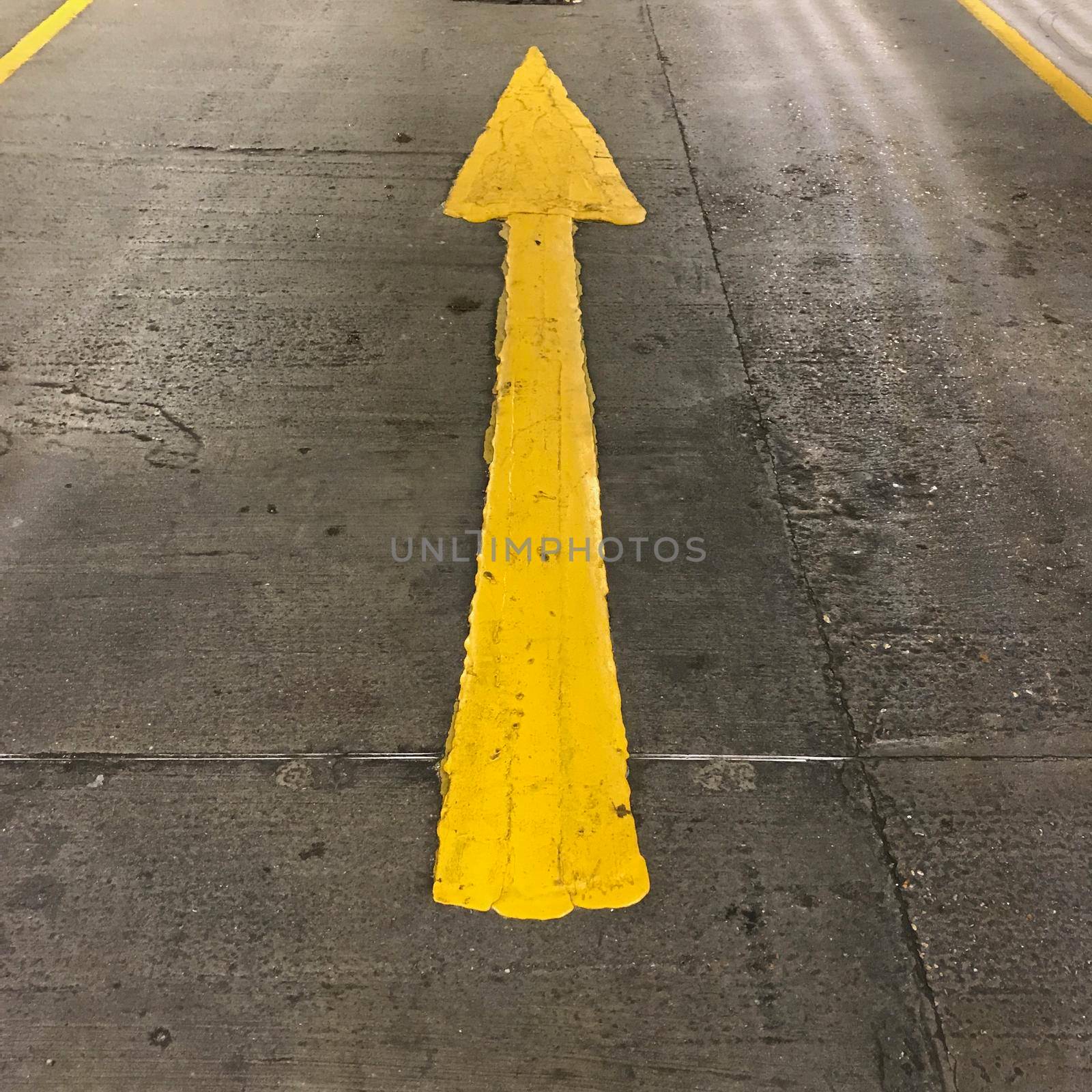 a Yellow arrow on the floor of a parking lot