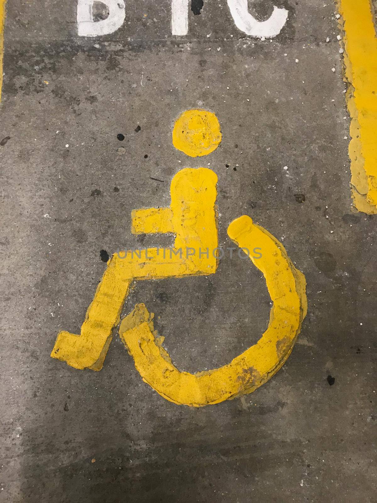 Sign of a yellow person and wheelchair on the floor in a parkinglot by LeoniekvanderVliet