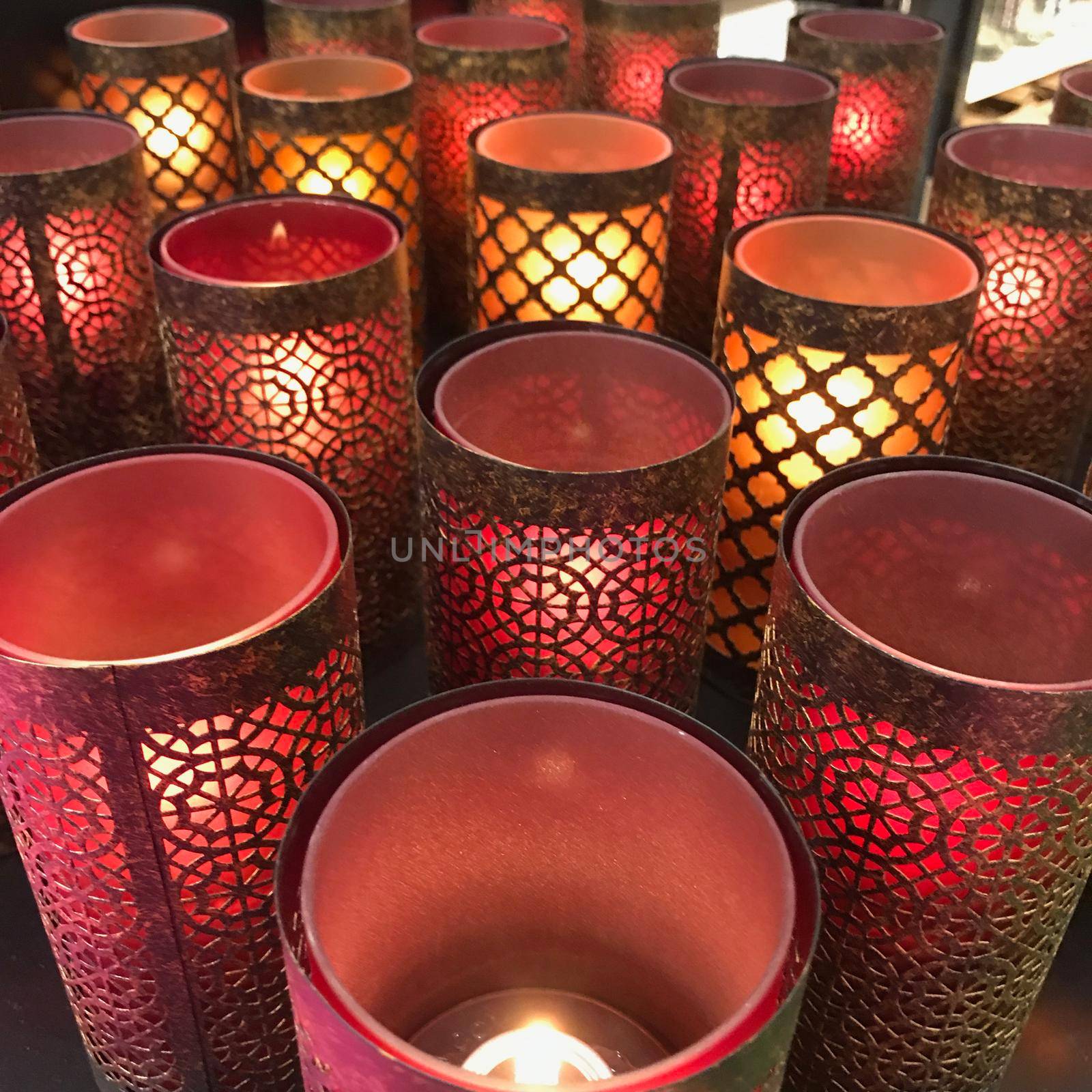 a Large group of red eastern candle holders with burning candles on a table