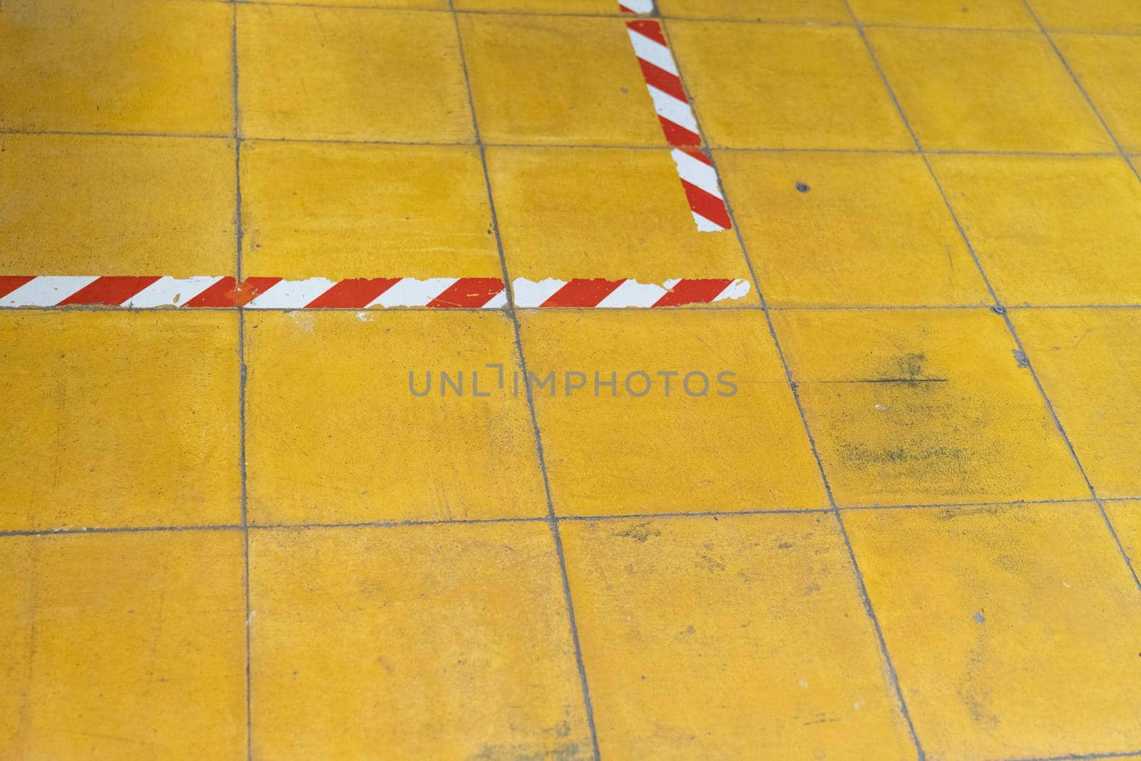 A yellow tiled floor with red and white tape