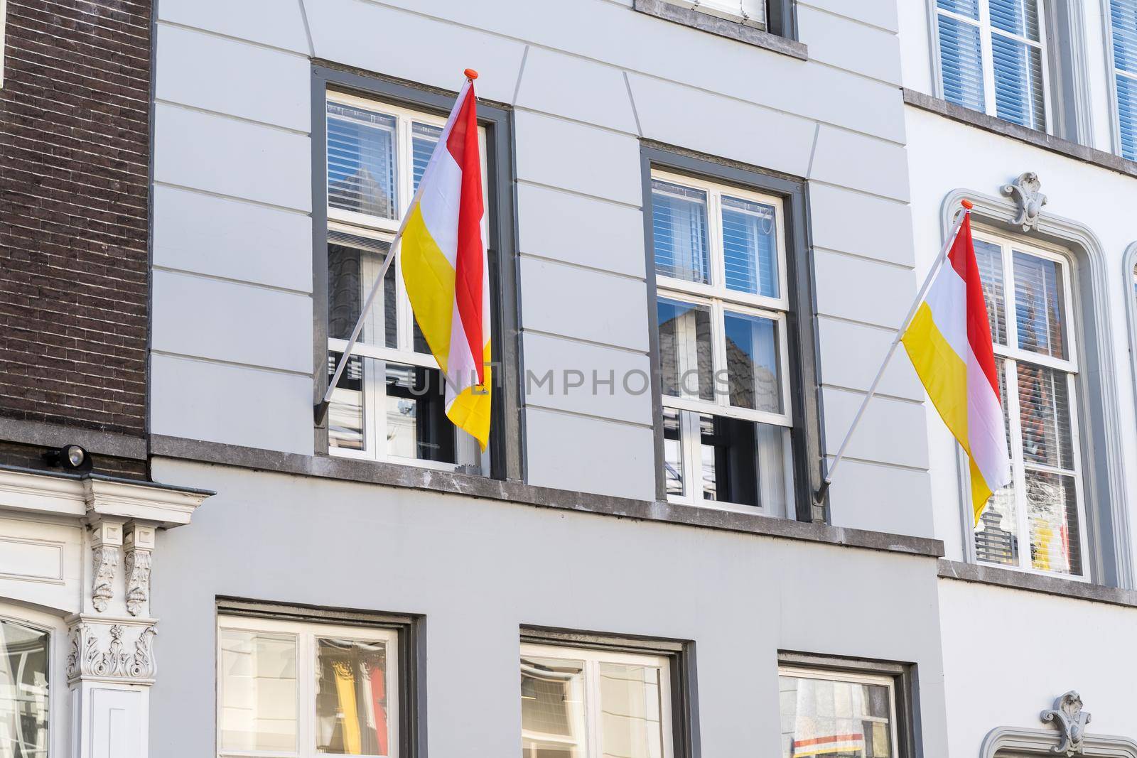 Dutch flags, in red, white and yellow, of traditional festival named Carnaval, like Mardi Gras, in 's-Hertogenbosch, Oeteldonk hanging on a building by LeoniekvanderVliet