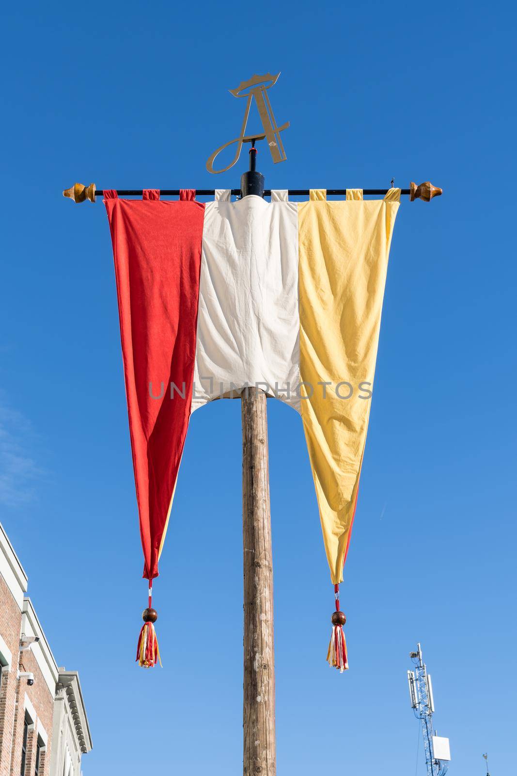 Dutch Flag, in red, white and yellow, of traditional festival named Carnaval, like Mardi Gras, in 's-Hertogenbosch, Oeteldonk with a blue sky  by LeoniekvanderVliet