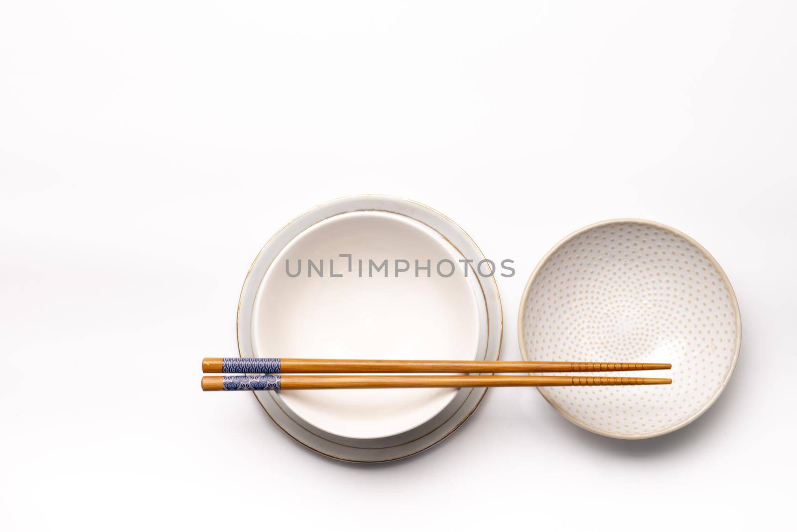 Three empty dishes or cups of blanc earthenware with chopsticks isolated on a white background seen from above or top view