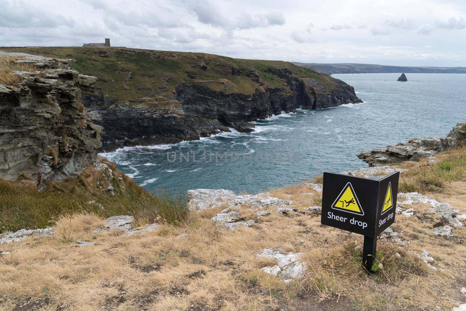 View from the top of cliffs in Cornwall, England, UK with a sign warning for danger becaise of sheer drop by LeoniekvanderVliet