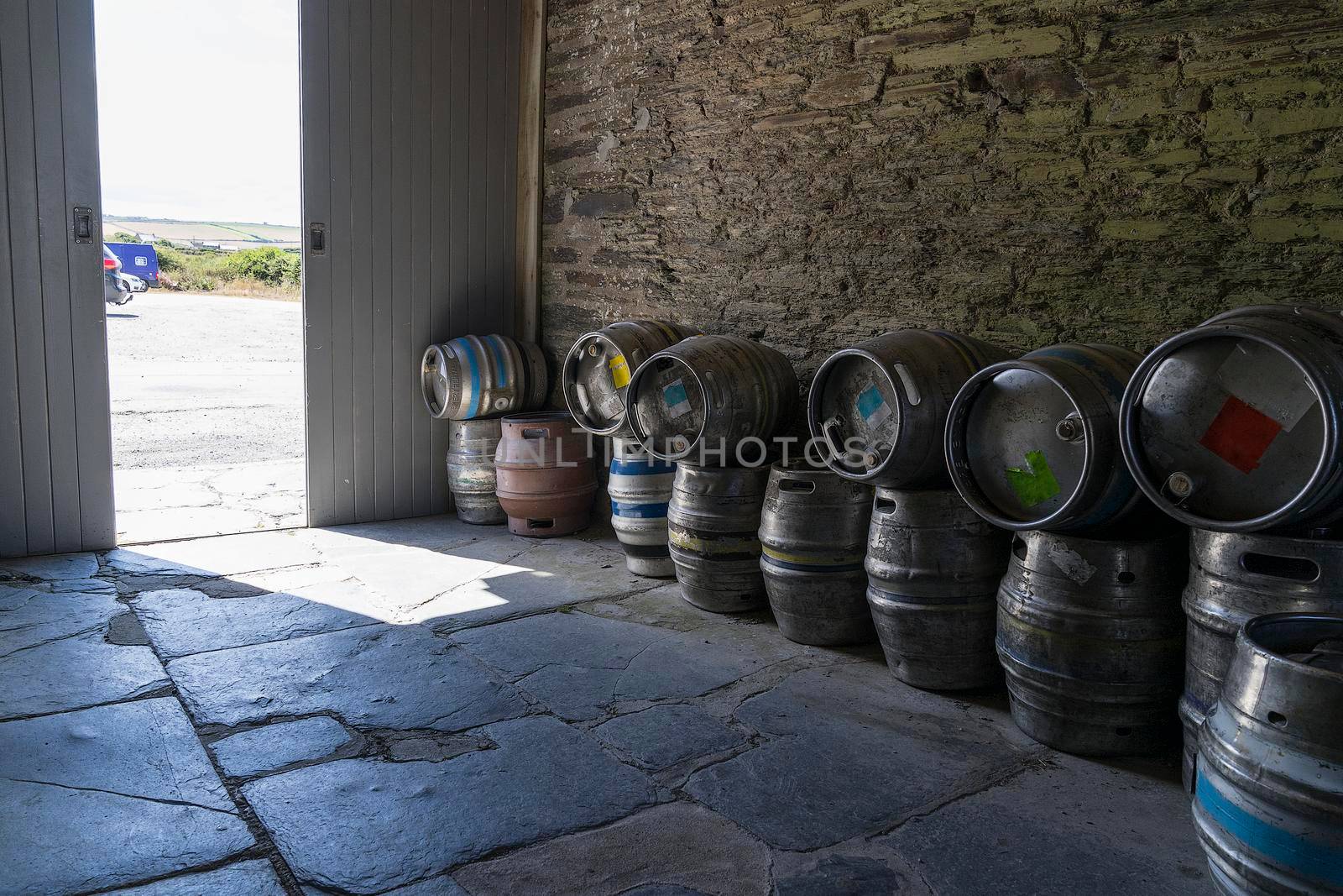 A stack or pile of empty beer casks or barrels storage outside a pub by LeoniekvanderVliet