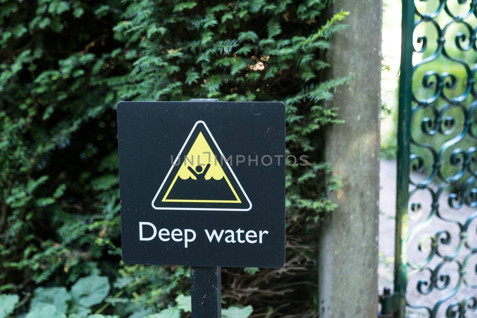 A warning sign in black and yellow indicating the danger of drowning in deep water forbidding people to swim, english language by LeoniekvanderVliet