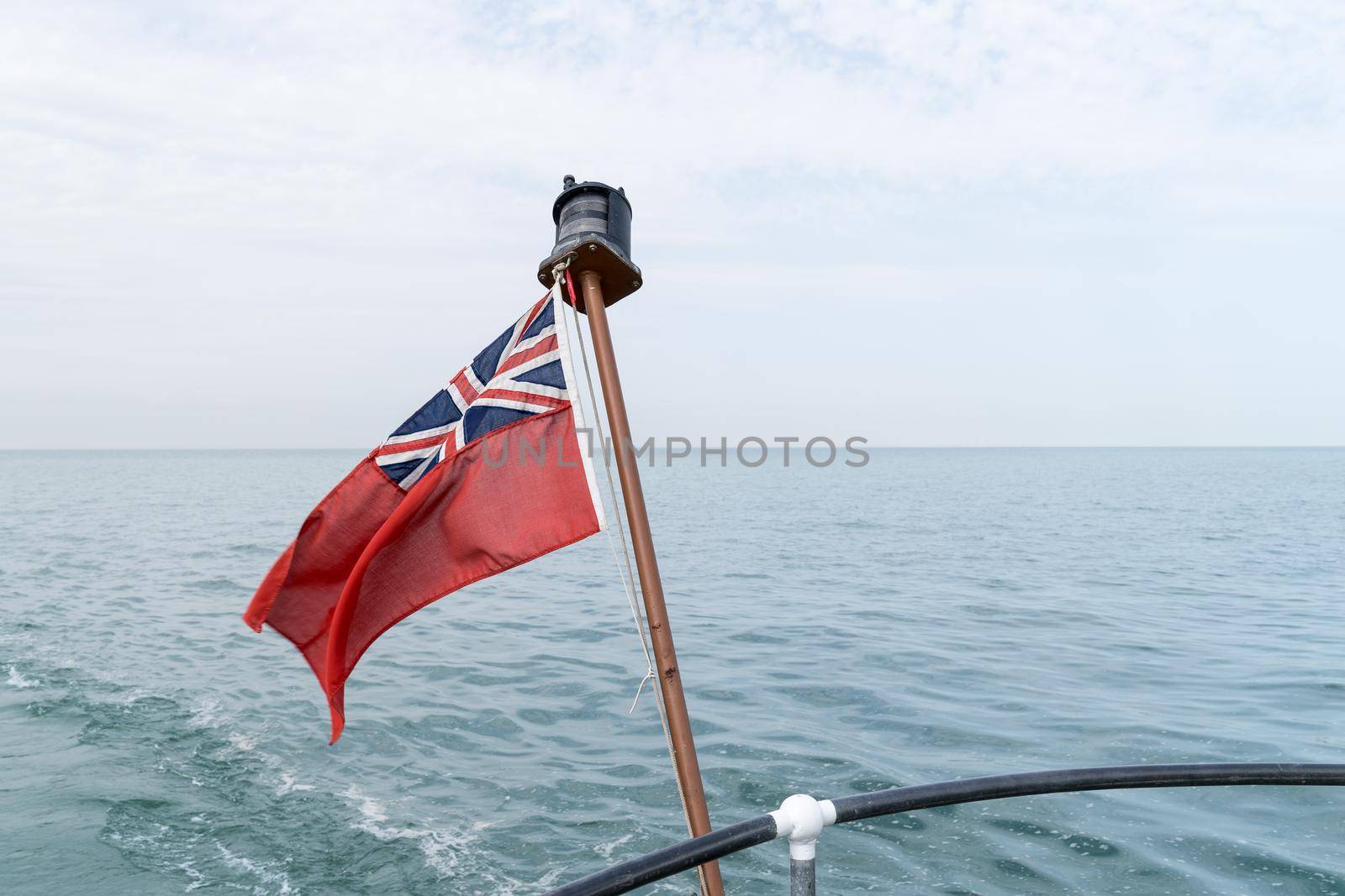 Uk red ensign the british maritime flag flown from yacht with the sea and sky behind it by LeoniekvanderVliet
