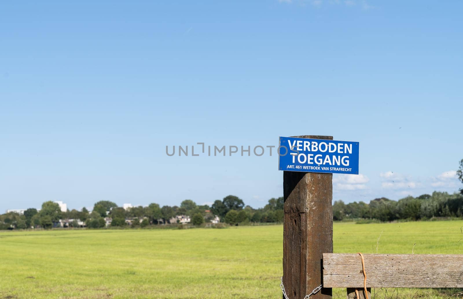 a Dutch `no entry` sign. Official `entrance forbidden` sign in the Netherlands saying in Dutch: "verboden toegang voor onbevoegden" attached to a fence at a farm with grassland