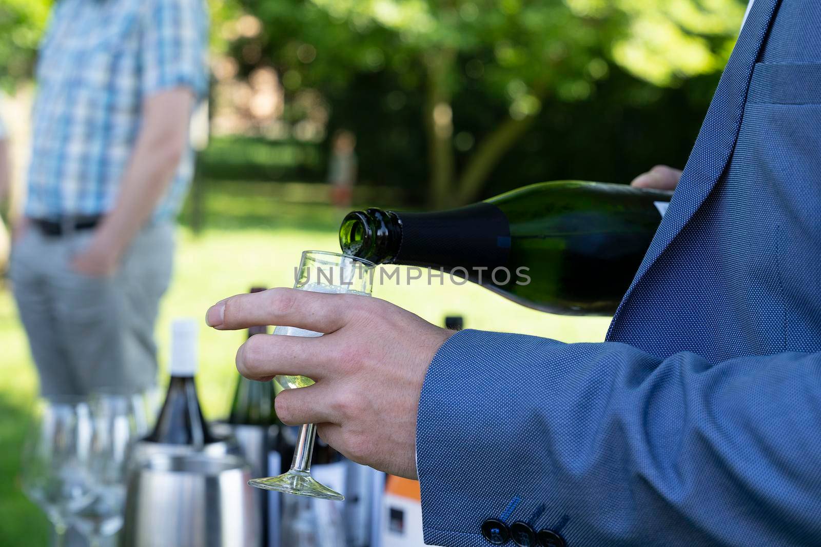 Male hands pooring white wine out of a bottle at an outdoor winetasting by LeoniekvanderVliet