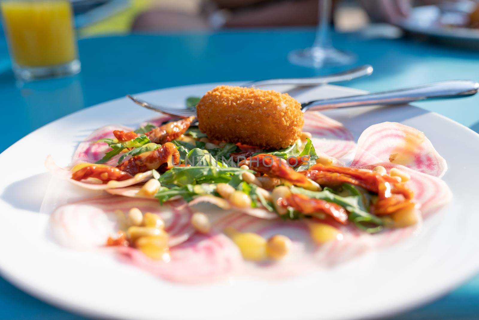 A white plate with a starter of croquette and salad typical Dutch fried food in culinary style by LeoniekvanderVliet