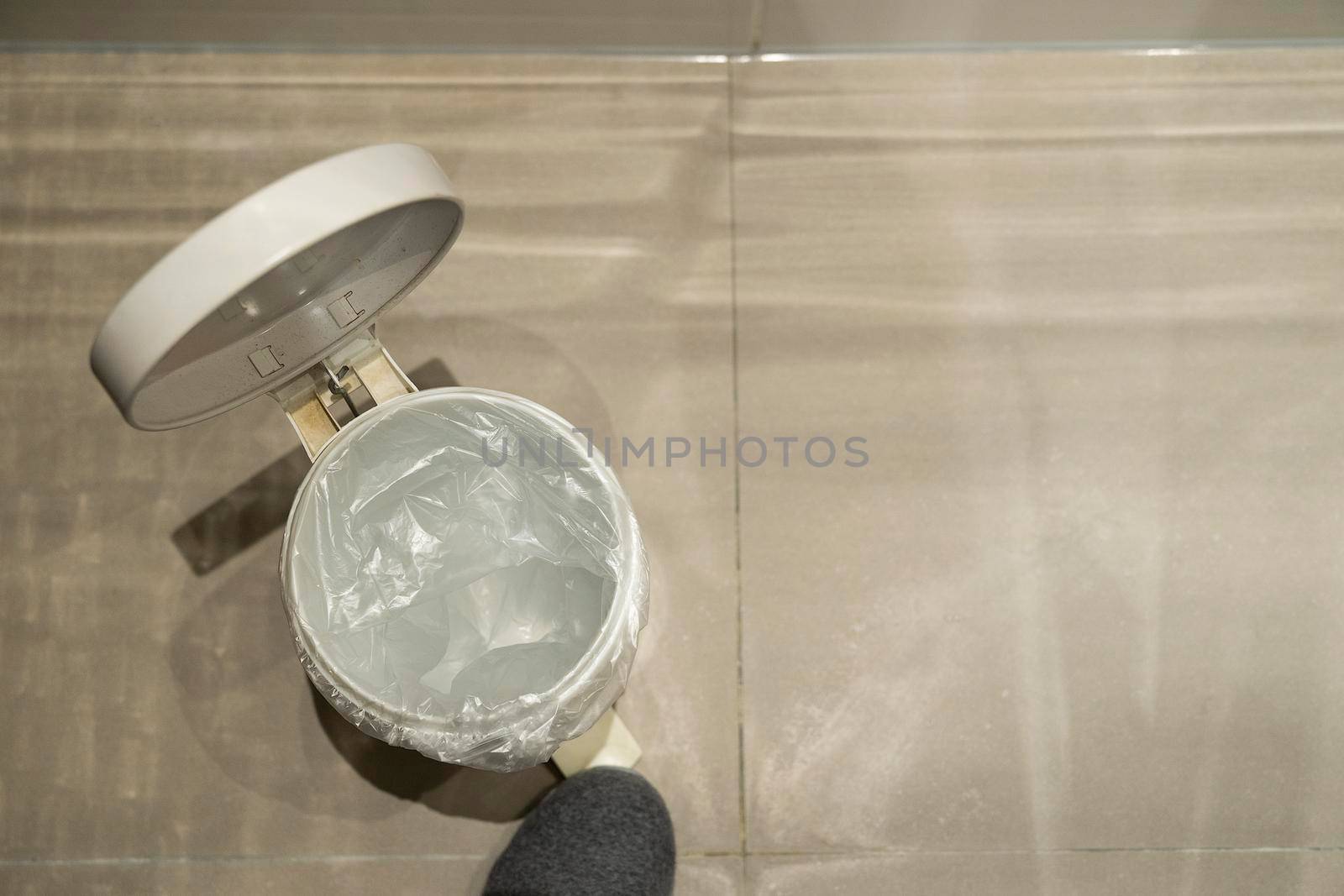 Foot opening a pedal bin which is empty seen from above with space for text by LeoniekvanderVliet