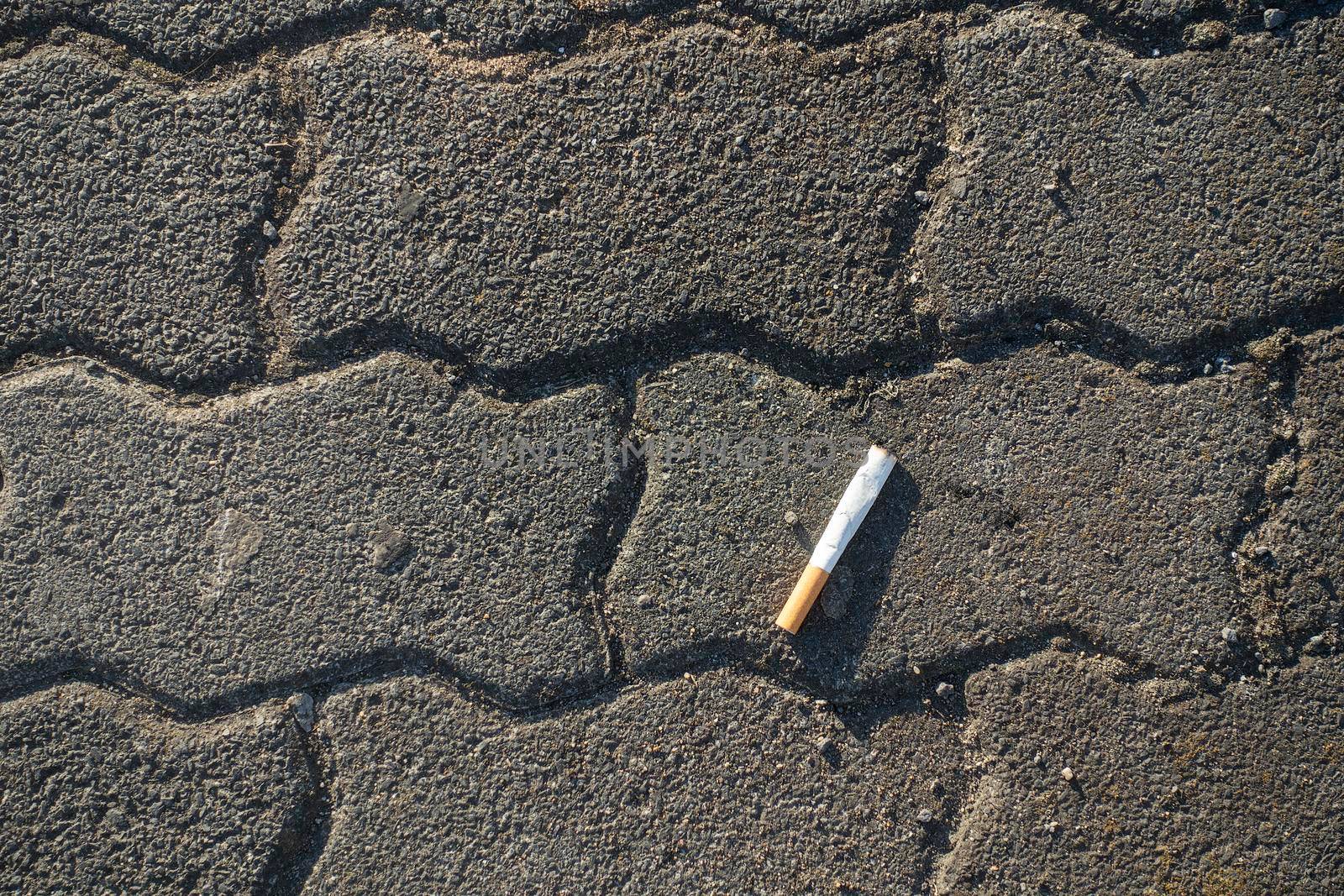Sigarette butt put out on the floor with bricks high angle view - concept for pollution and bad health habits addiction