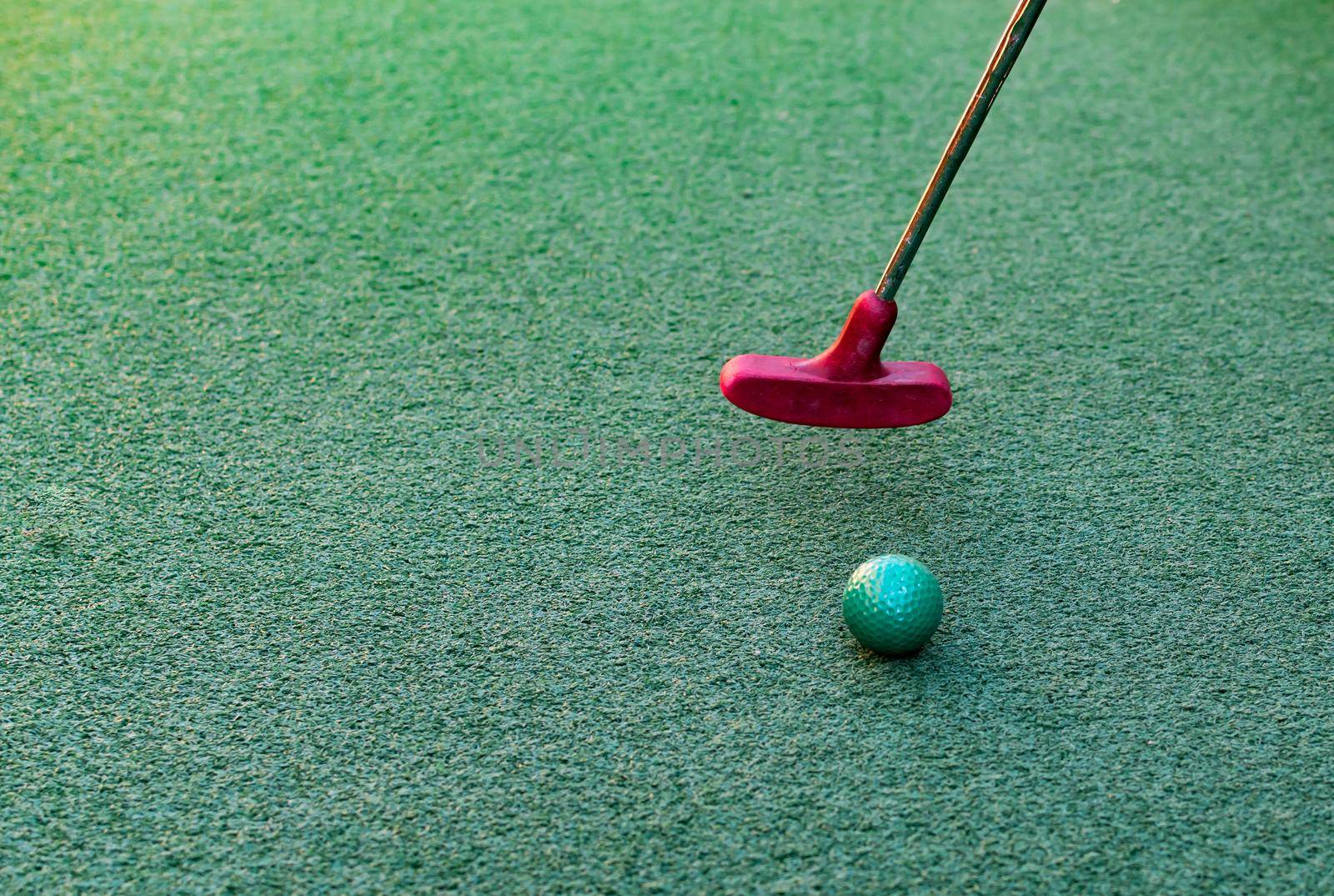 Closeup of toy golf ball and putter on the green grass by billroque