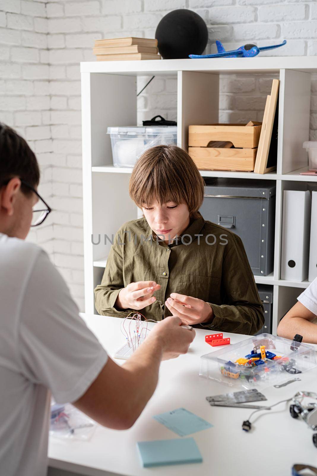 Young boys and teacher having fun constructing robot cars together at the workshop