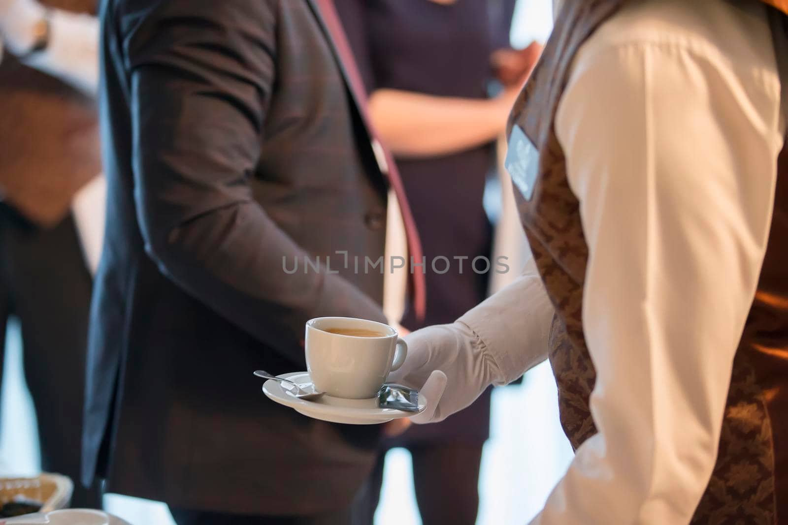 Waiter's hands with a cup on the background of a man