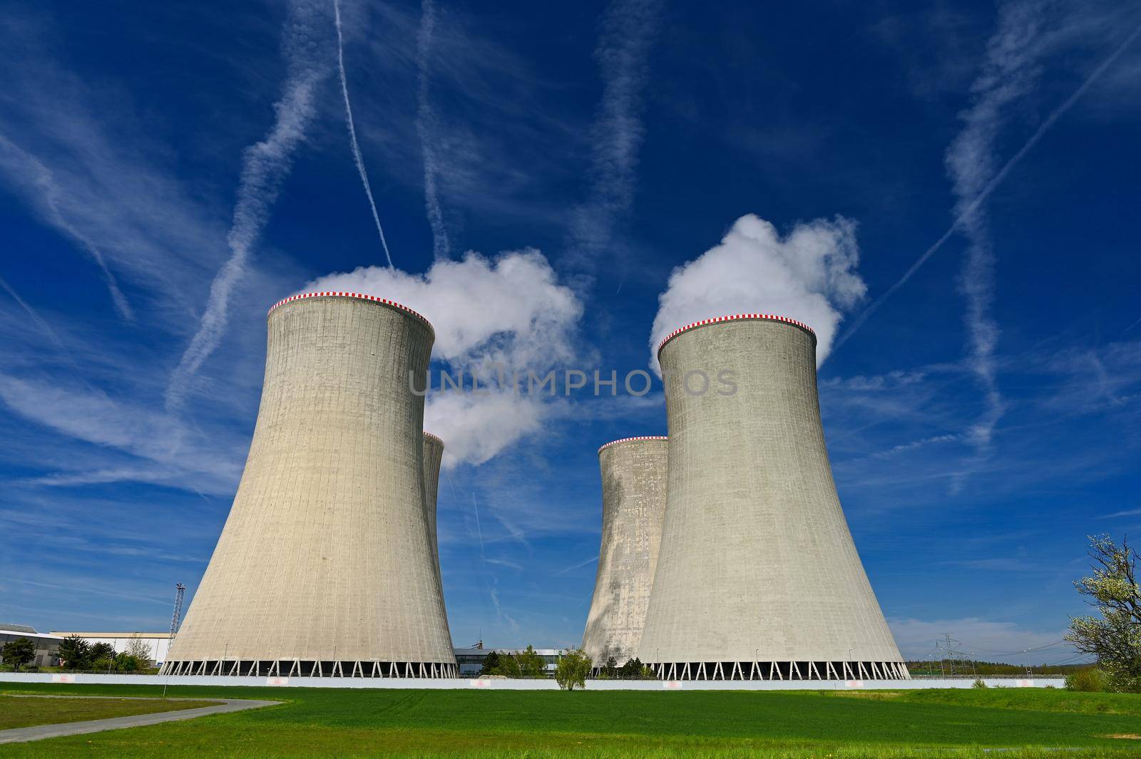 Dukovany Nuclear Power Plant - Czech Republic.
Large chimneys with blue sky and smoke. Concept for industry and environment.