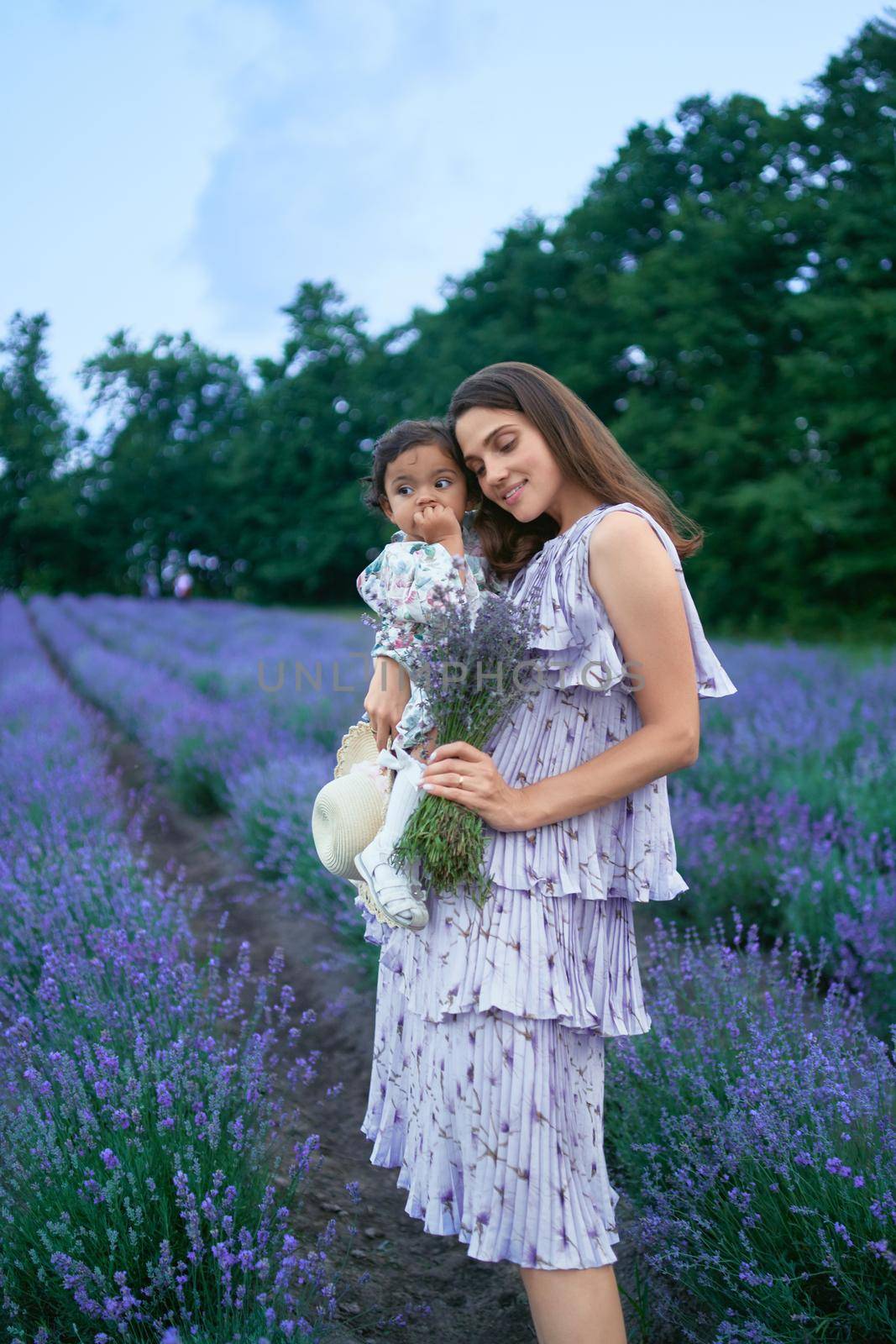 Mother carrying little daughter and lavender bouquet. by SerhiiBobyk