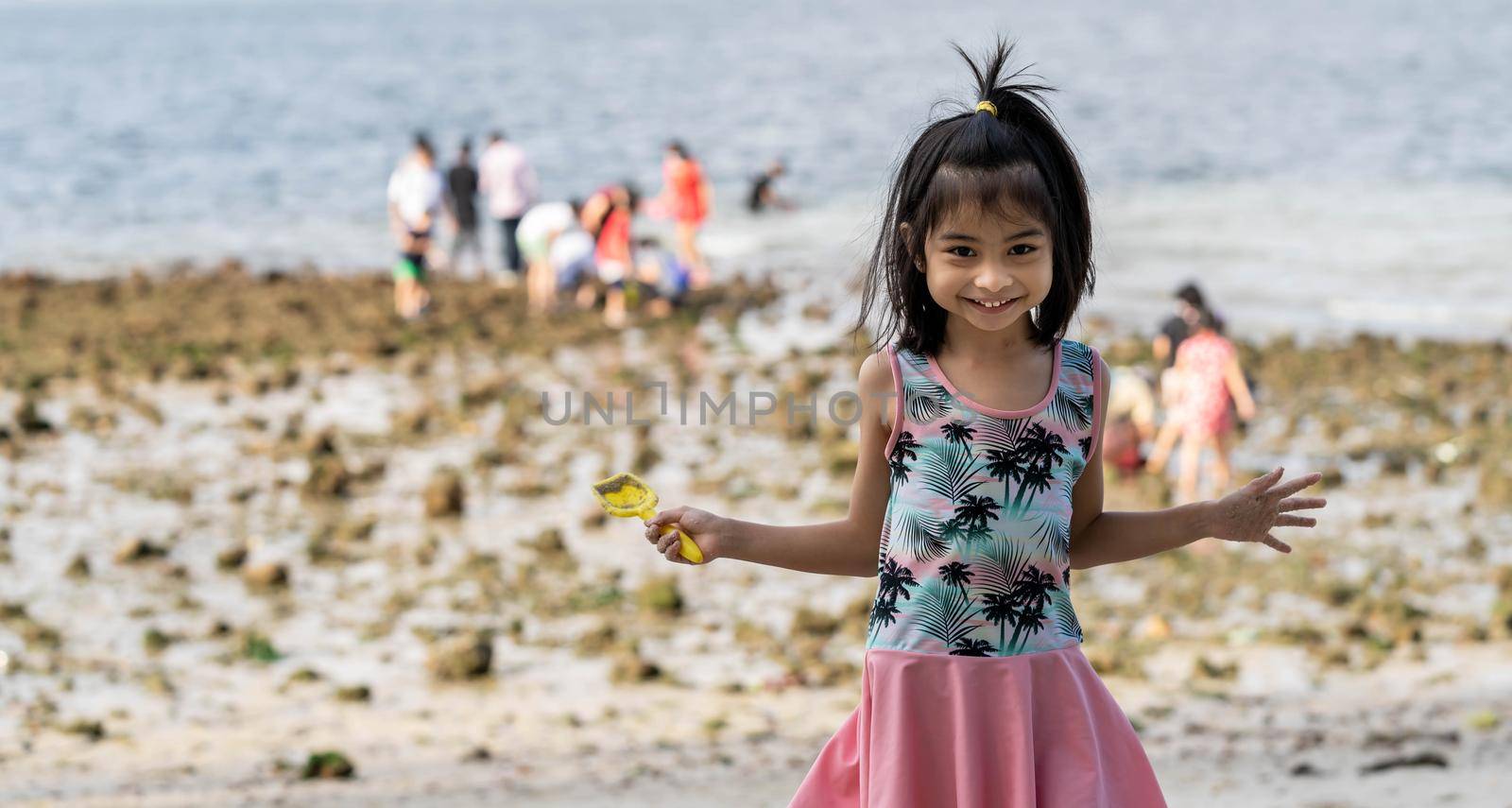 Happy little girl in the beach holding beach toy and colorful swimming suit. by billroque