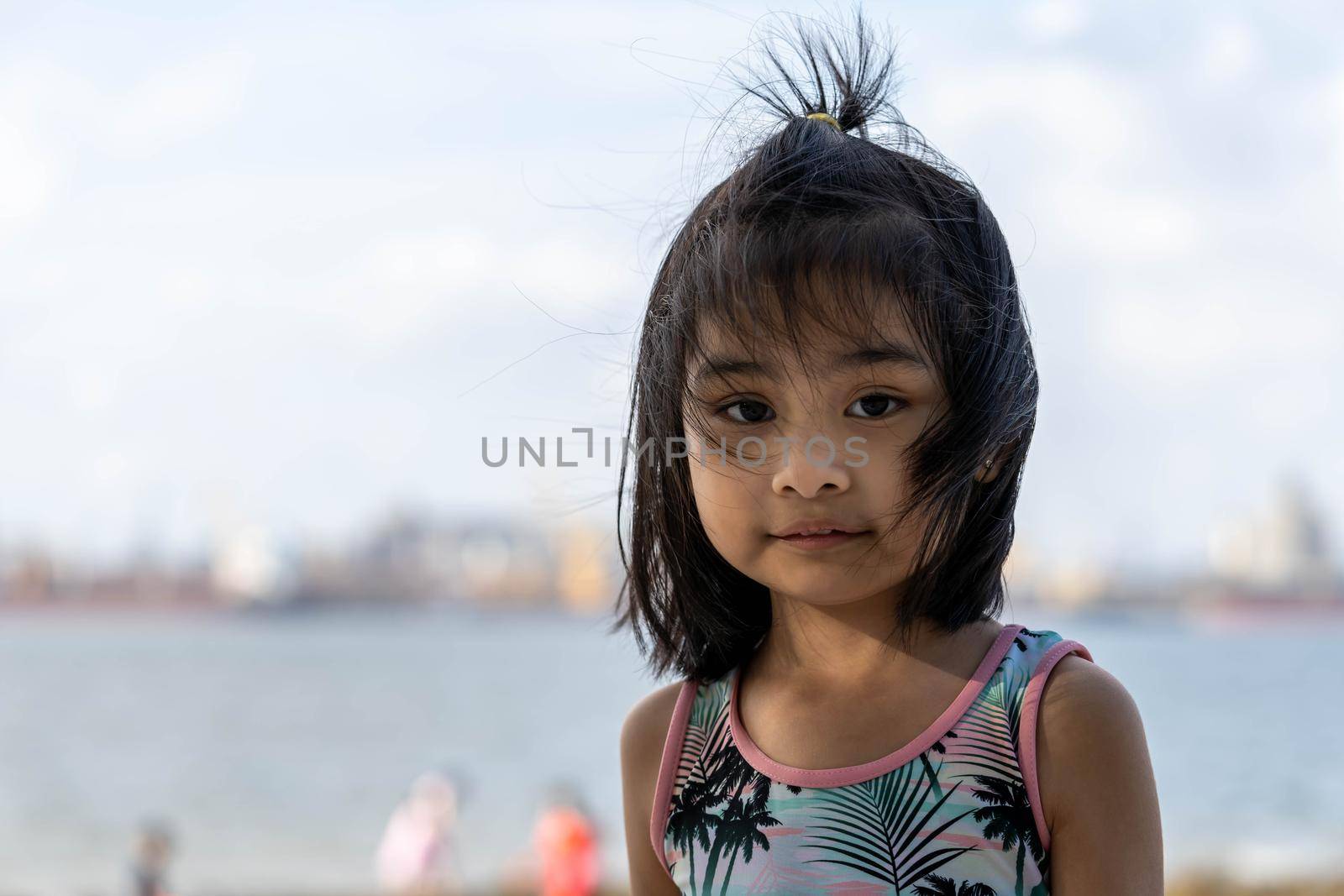 Pretty little asian girl in the beach with blurry background and colorful swimming suit. by billroque