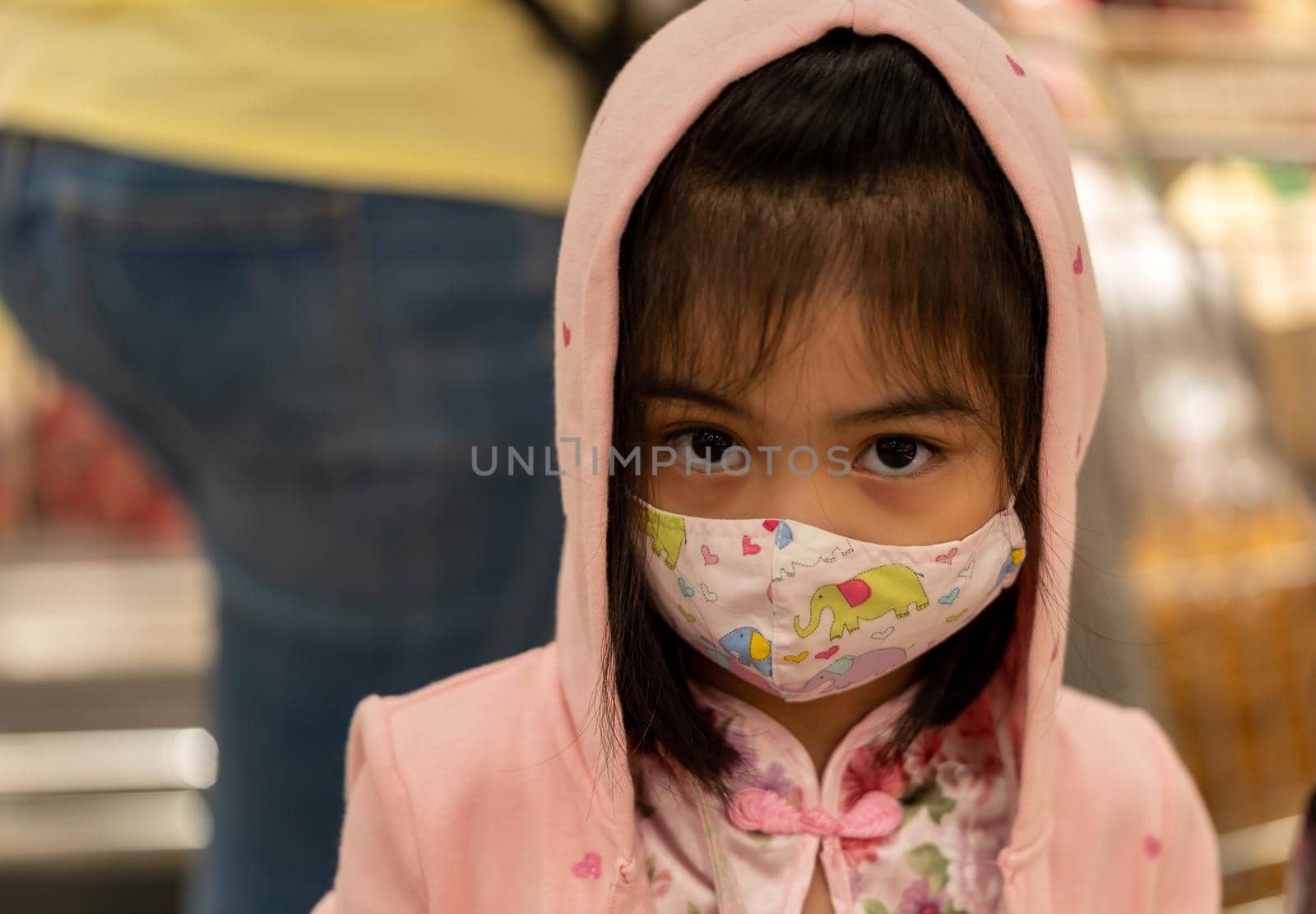 Little girl with fabric mask protect herself from Coronavirus when child go to supermarket. Little asian girl wearing mask in a market