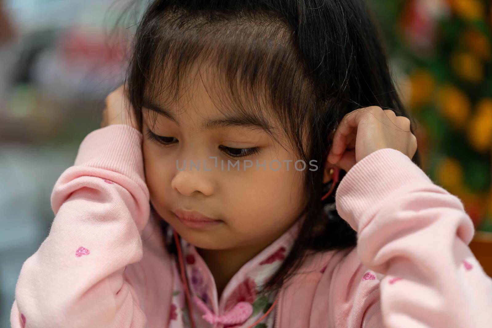 Cute Asian little girl while listening to music wearing earphone by billroque