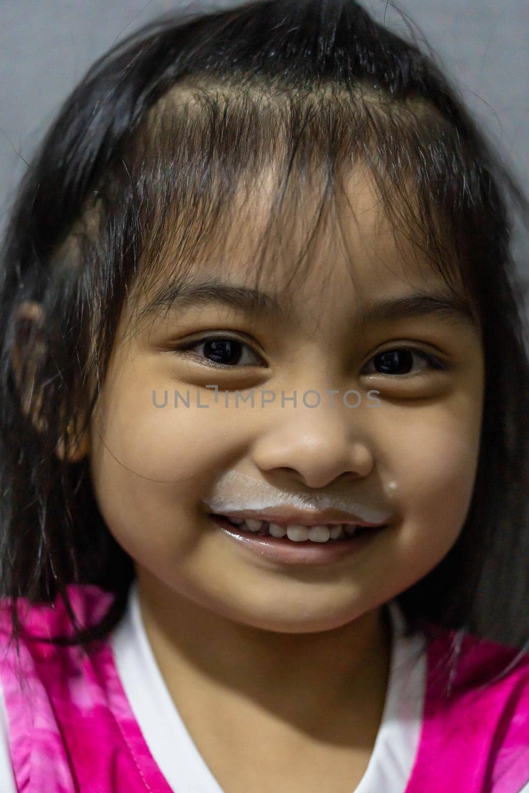 Young girl enjoying a fresh glass of milk displaying a white mustache.