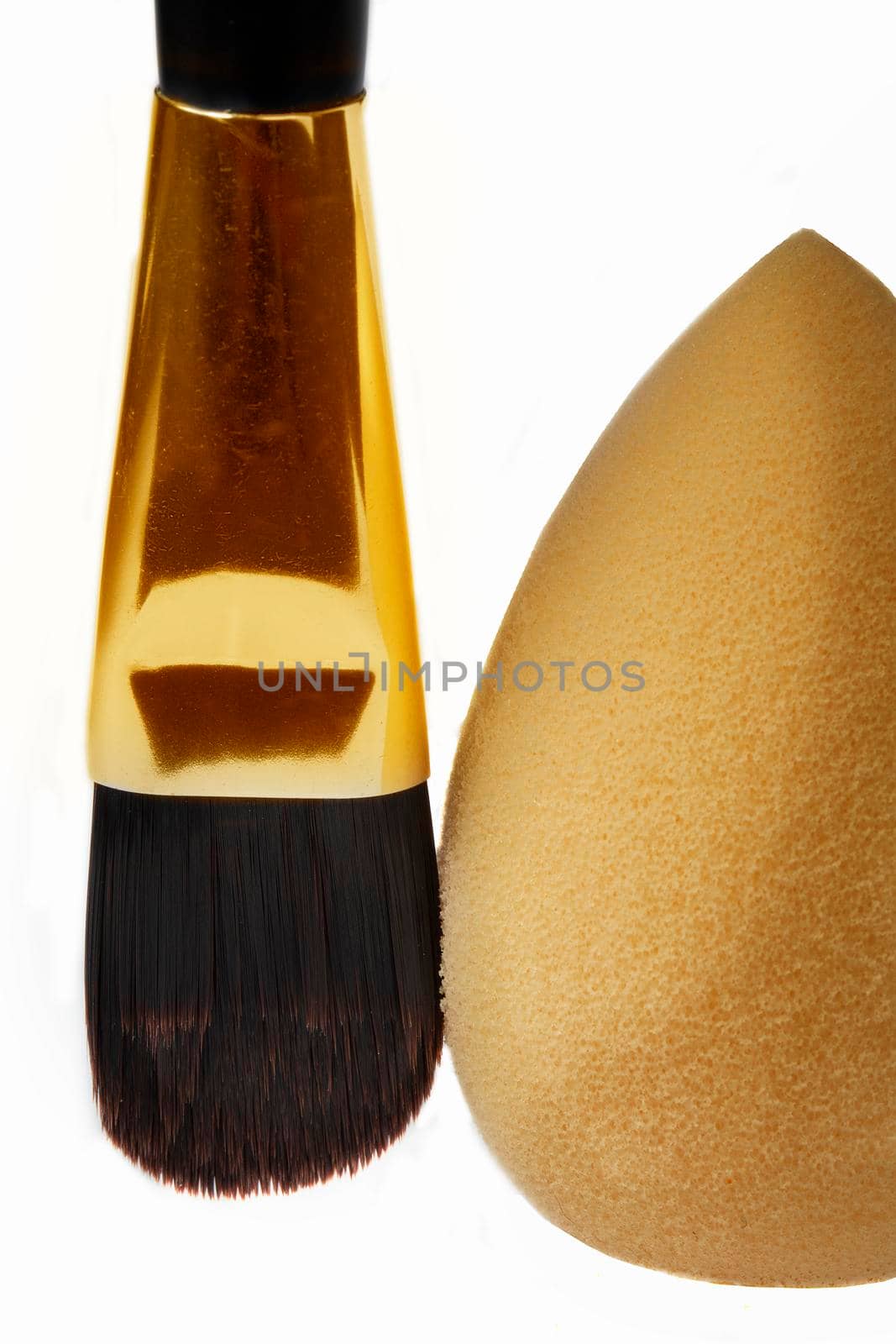 Cosmetic brush and face sponge vertically on a white background. Means for applying cosmetics.
