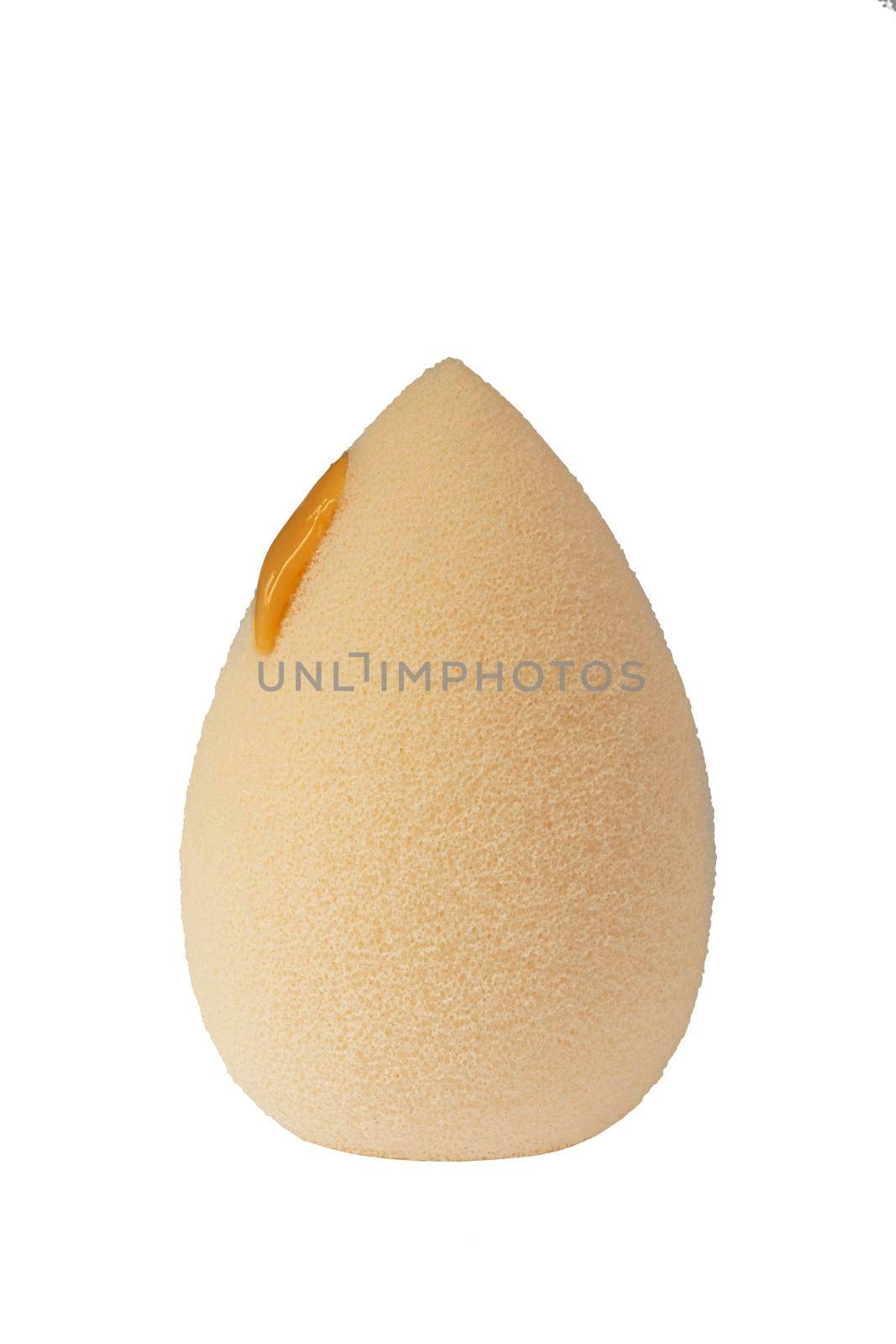 Cosmetic face sponge with a drop of foundation cream isolated on a white background.