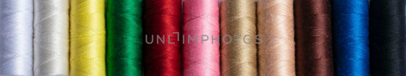 Colorful sewing threads in a row for a banner. The texture of multi-colored threads. by Sviatlana