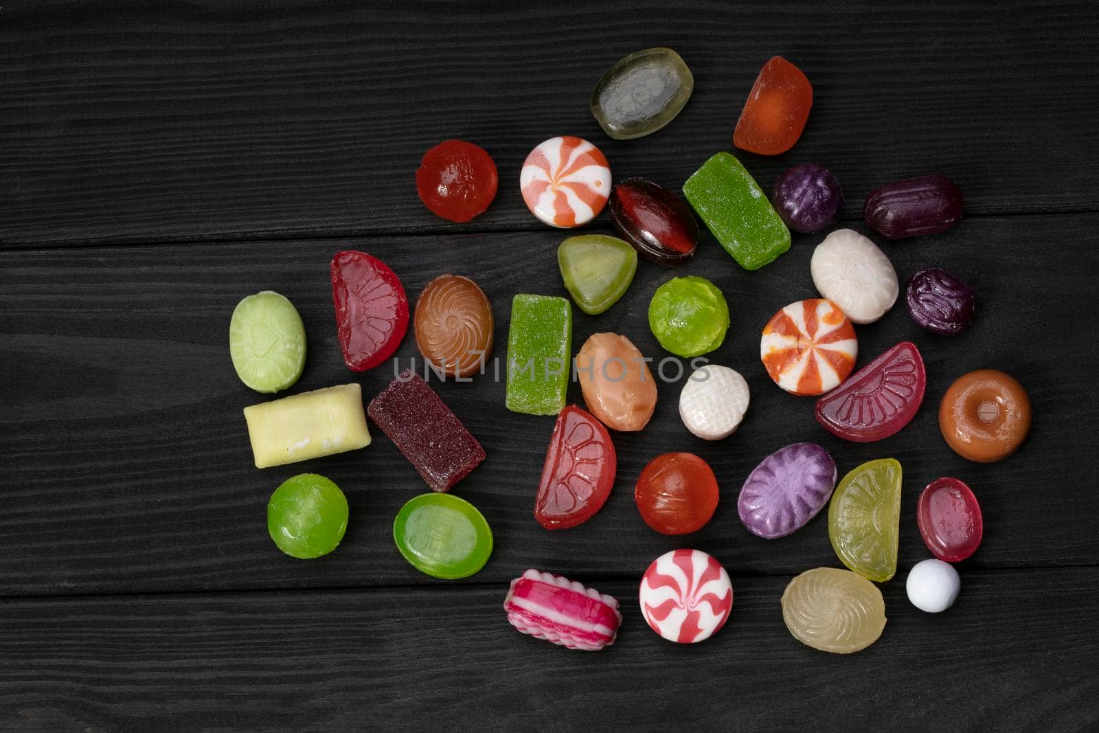 Candies on a dark background. Multi-colored caramel on a wooden board. Sweets.
