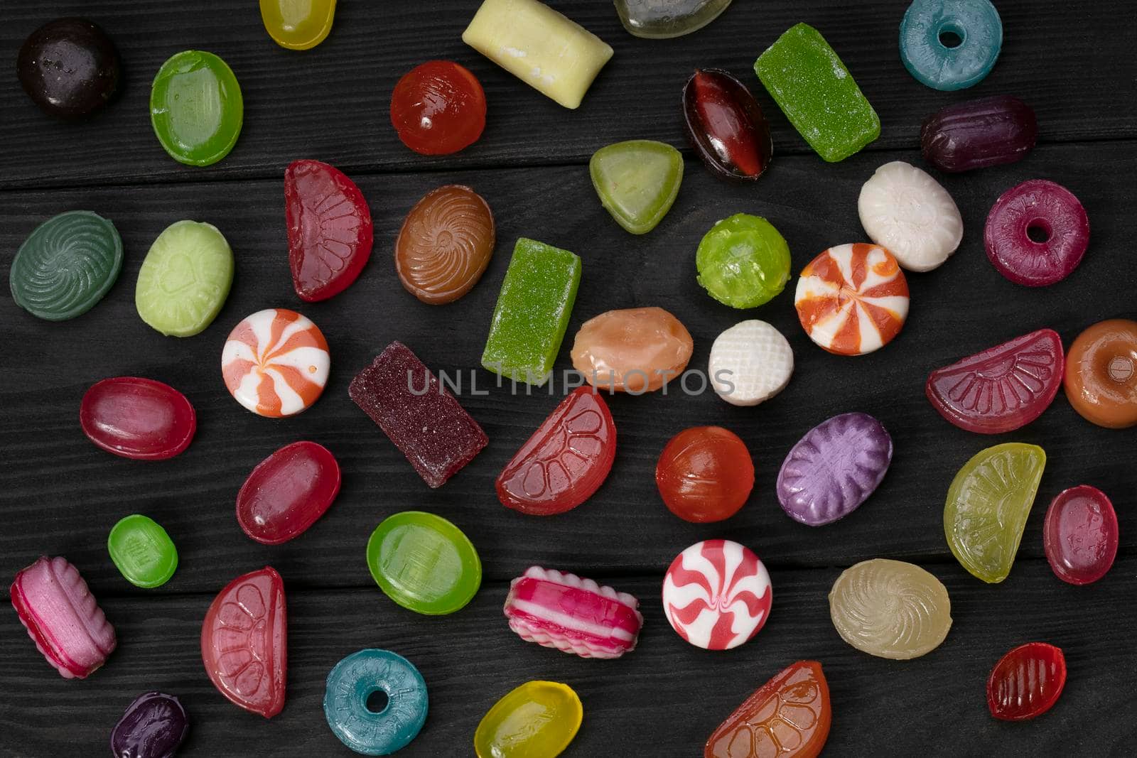 Candies on a dark background. Multi-colored caramel on a wooden board. Sweets.