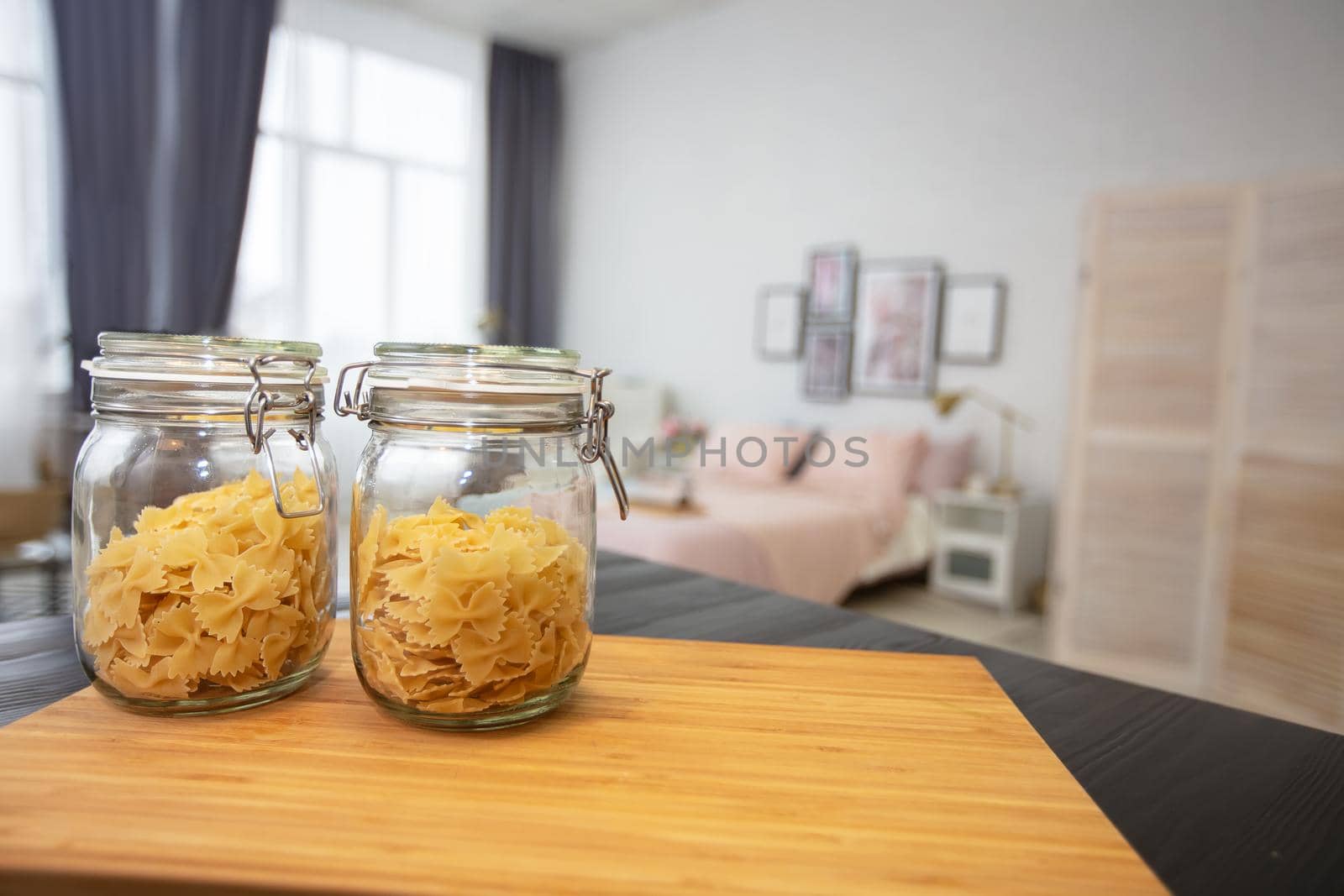 Jars of pasta on the background of the bedroom. Morning in the studio apartment.
