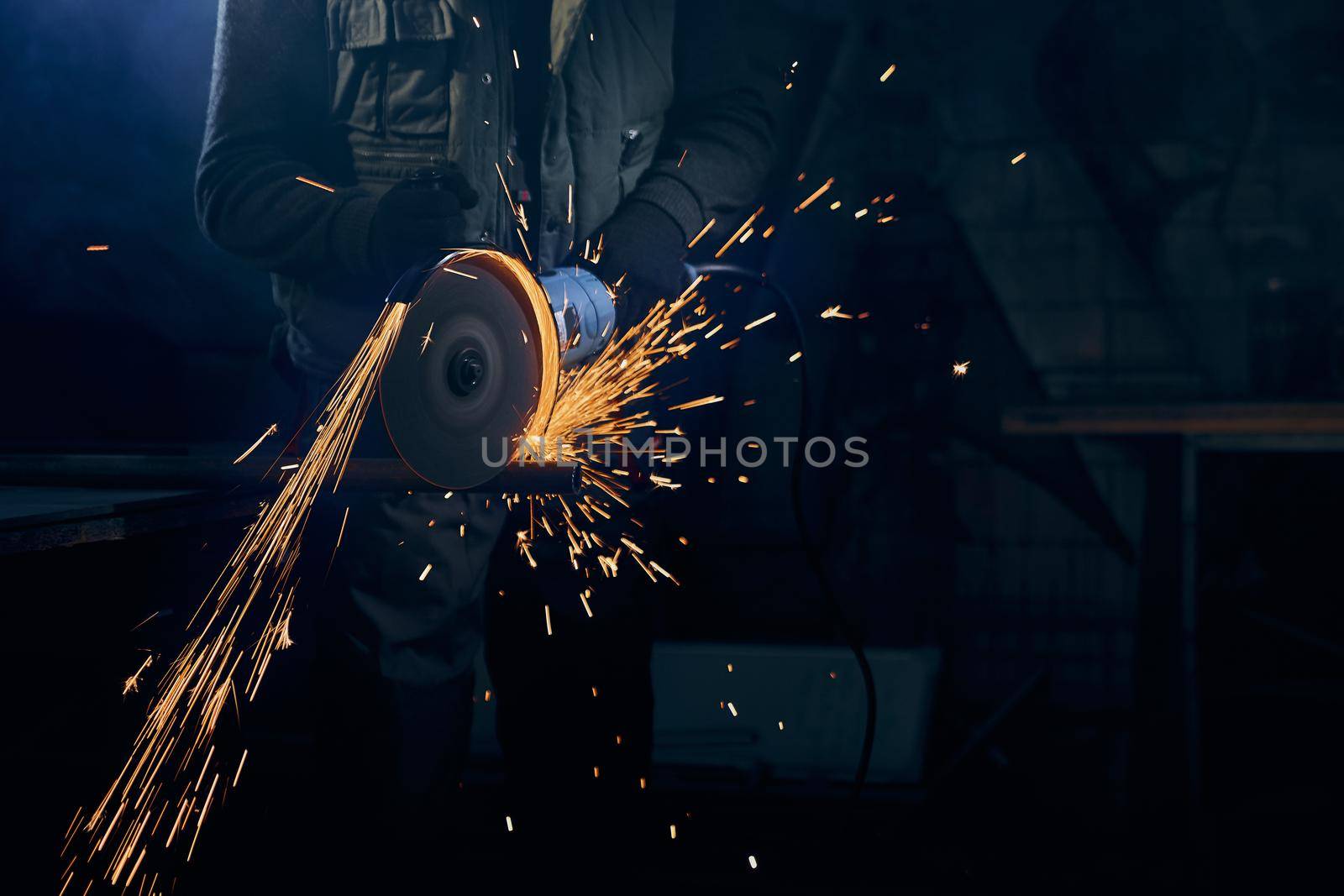 Young man cutting with rotating disc for metal with sparks. by SerhiiBobyk
