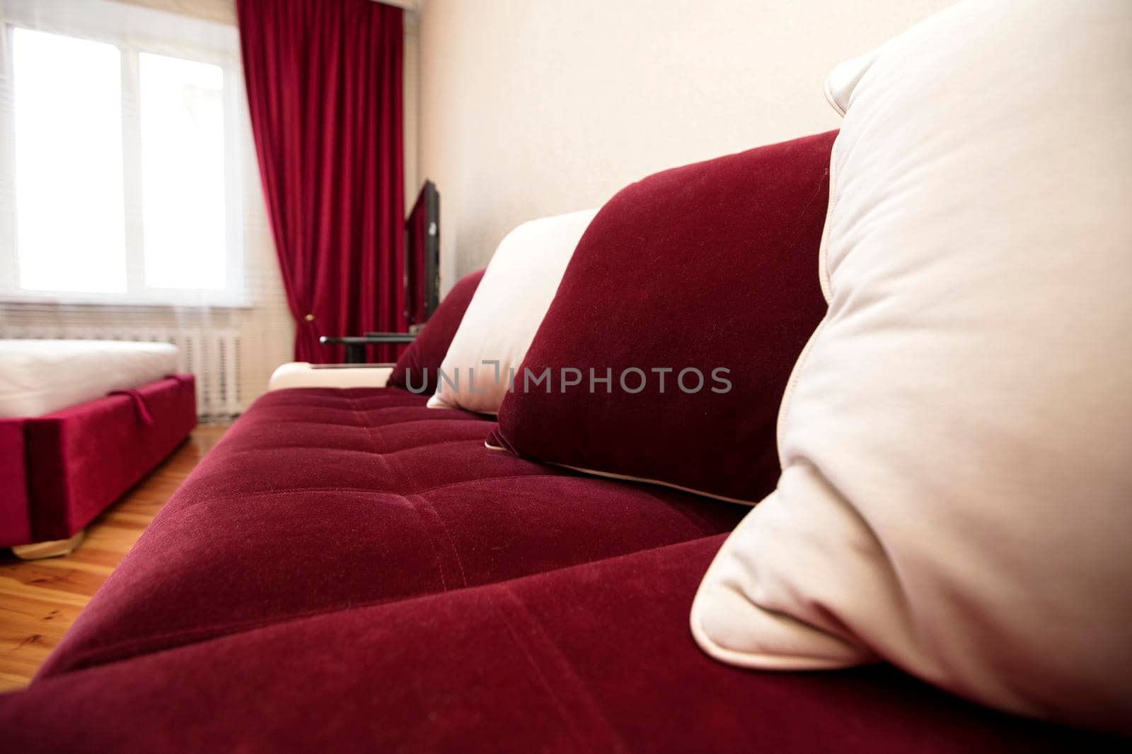 Part of a red sofa with white pillows in the living room.