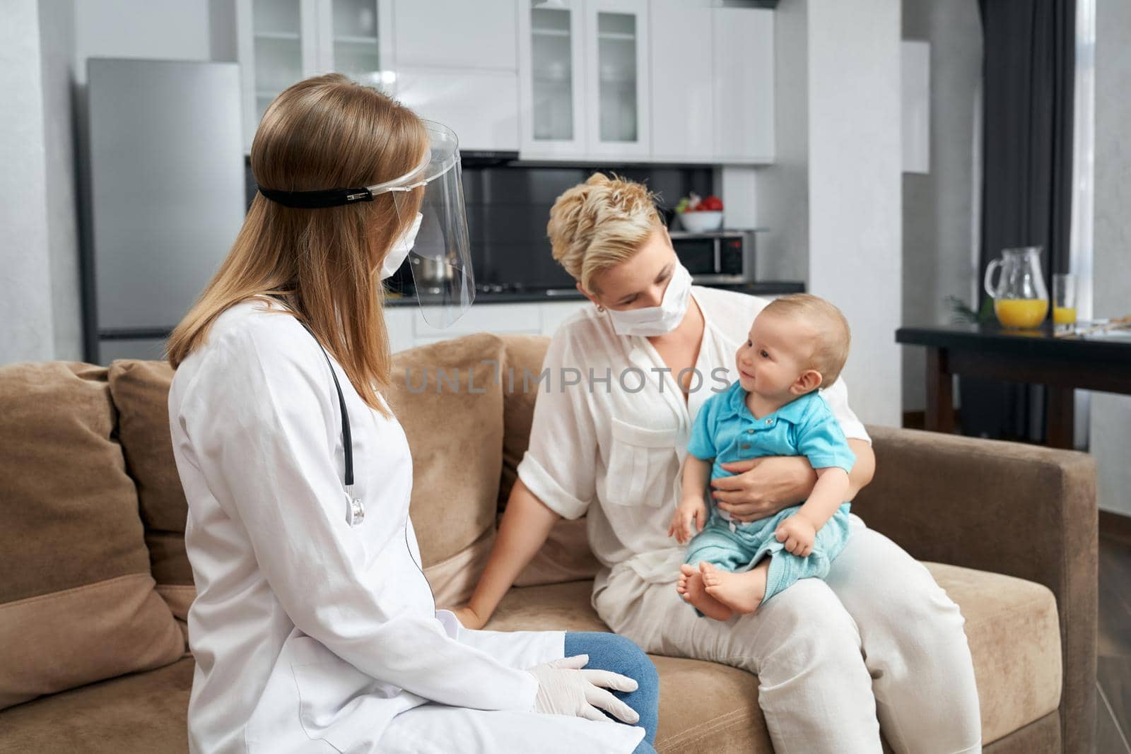 Pediatrician in medical mask visiting baby at home by SerhiiBobyk