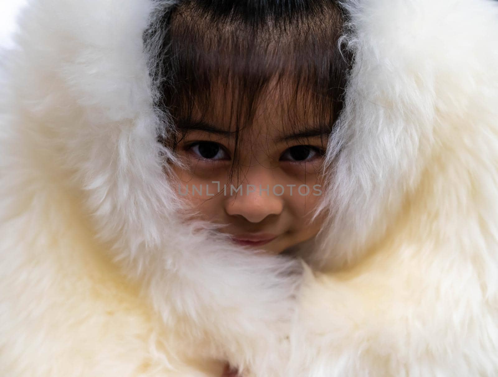 Pretty asian child wearing a white coat made of fur. Pretty asian model wearing white fur coat