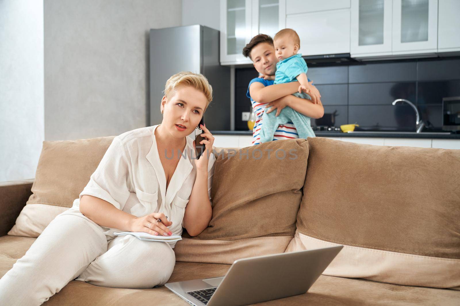 Busy mother working at home while her sons playing near by SerhiiBobyk