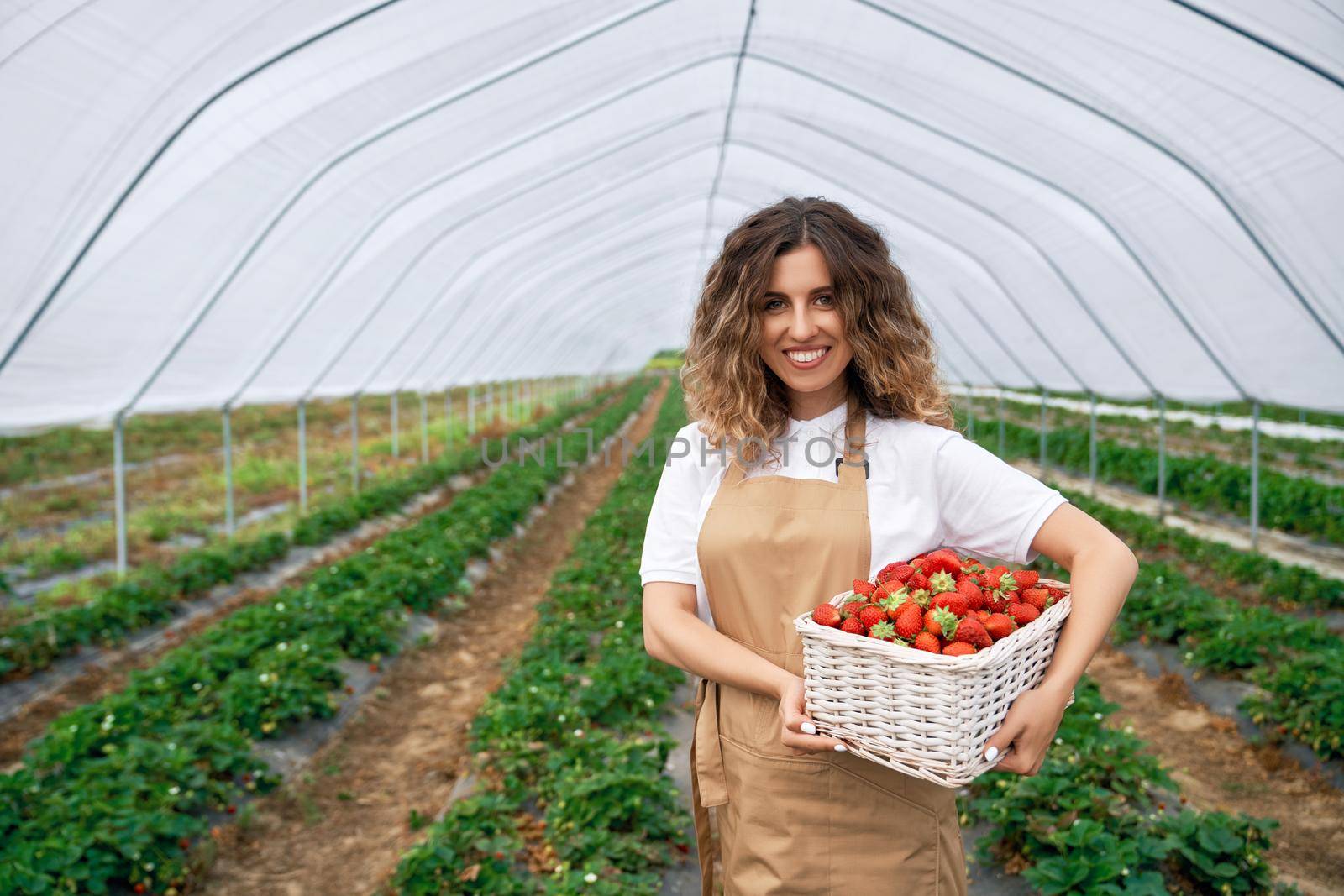 Smiling woman is holding basket with strawberries. by SerhiiBobyk