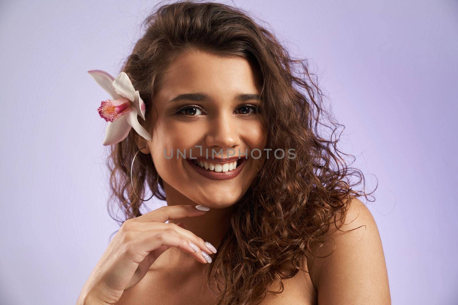 Smiling female model with orchid behind ear. by SerhiiBobyk